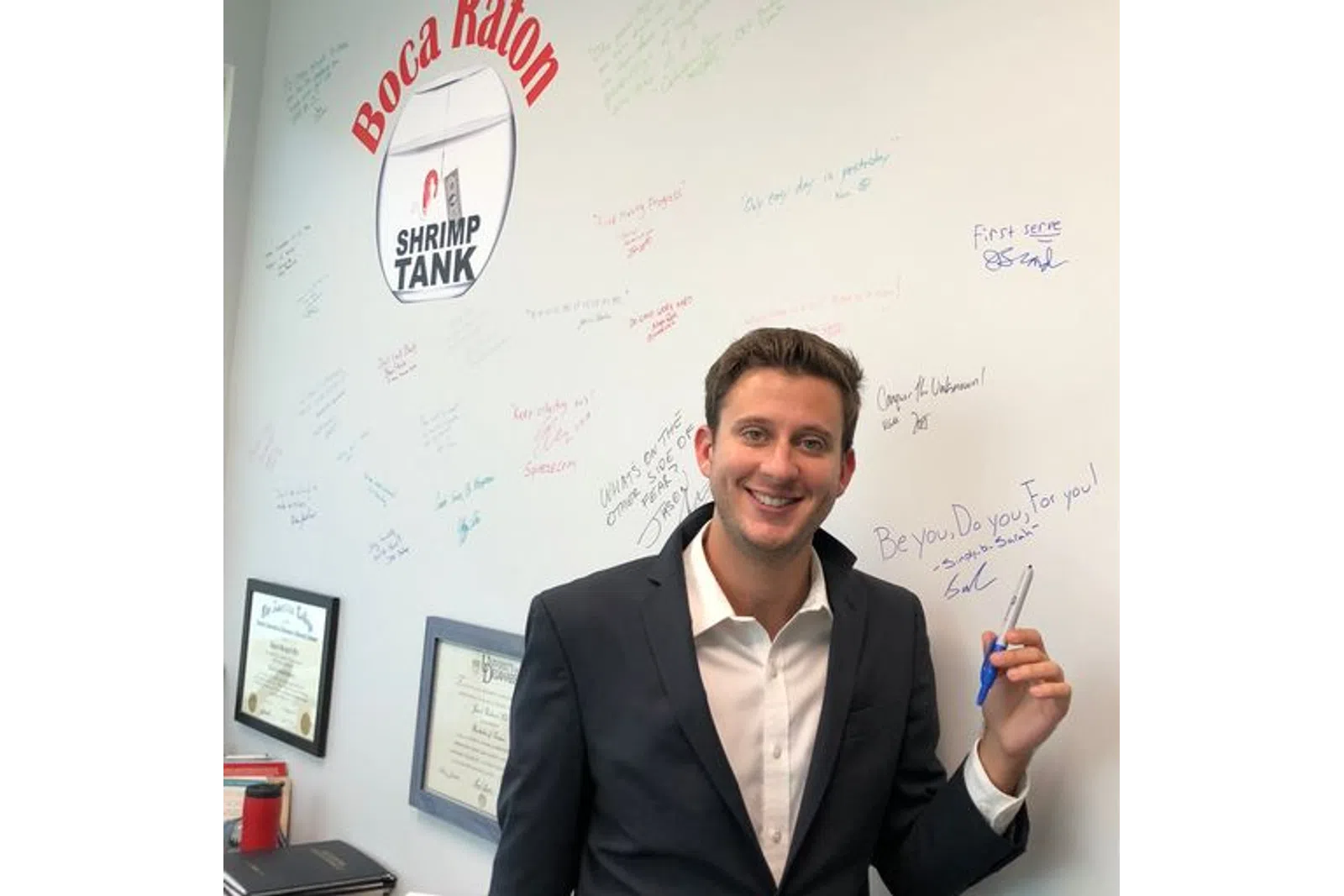 a man holding a pen and standing in front of a whiteboard