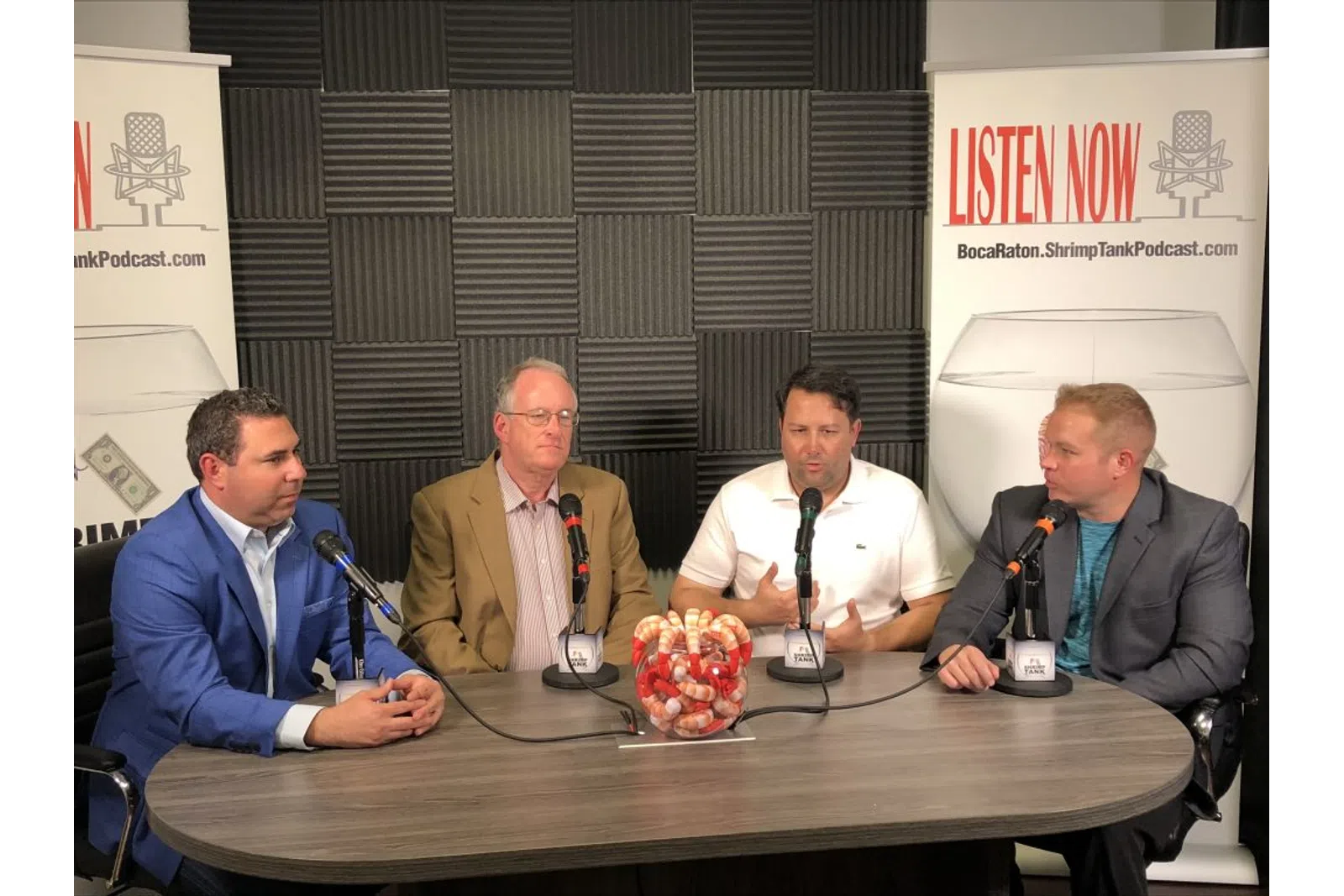 a group of men sitting at a table with microphones