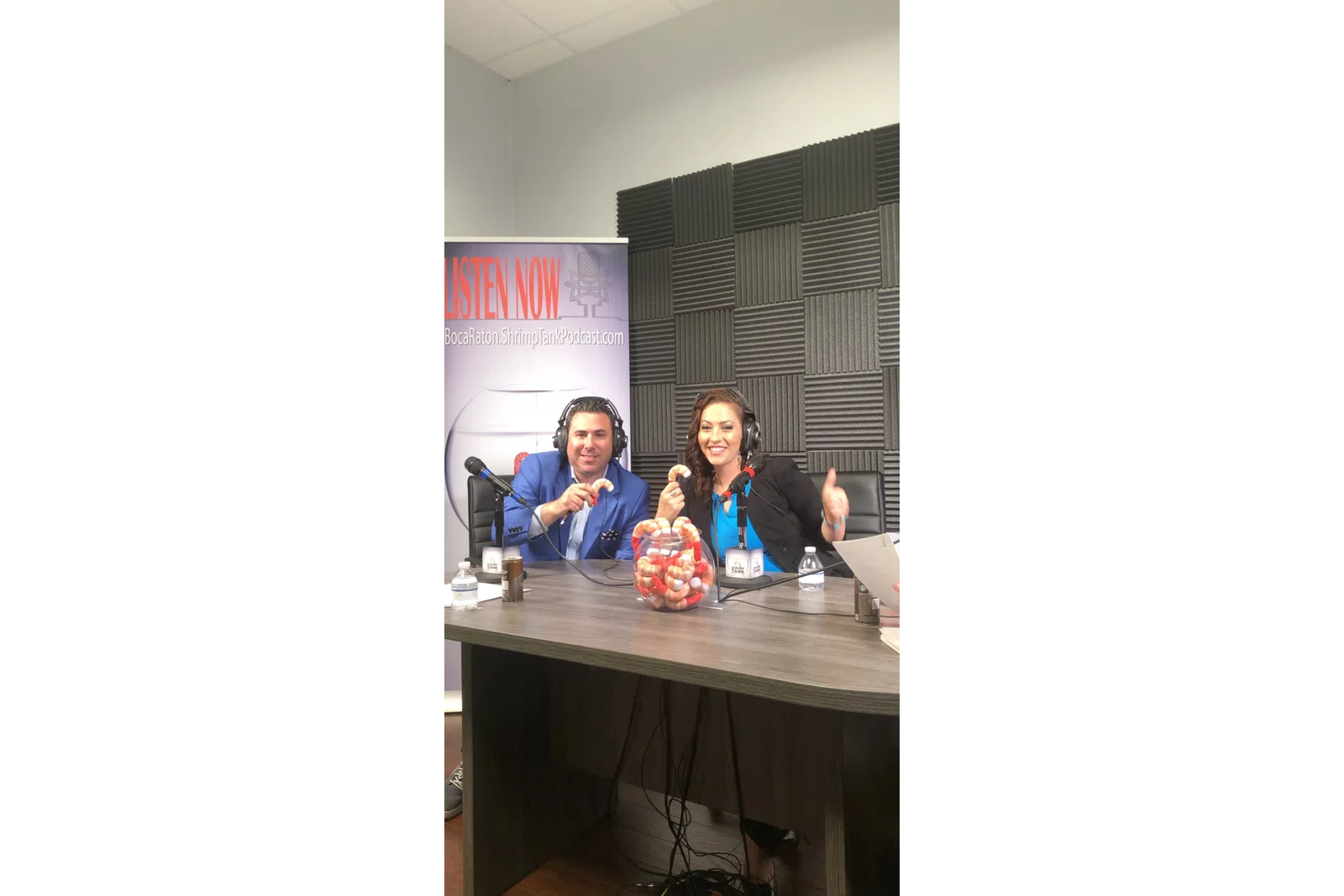 a man and woman sitting at a table with microphones and a basket of eggs