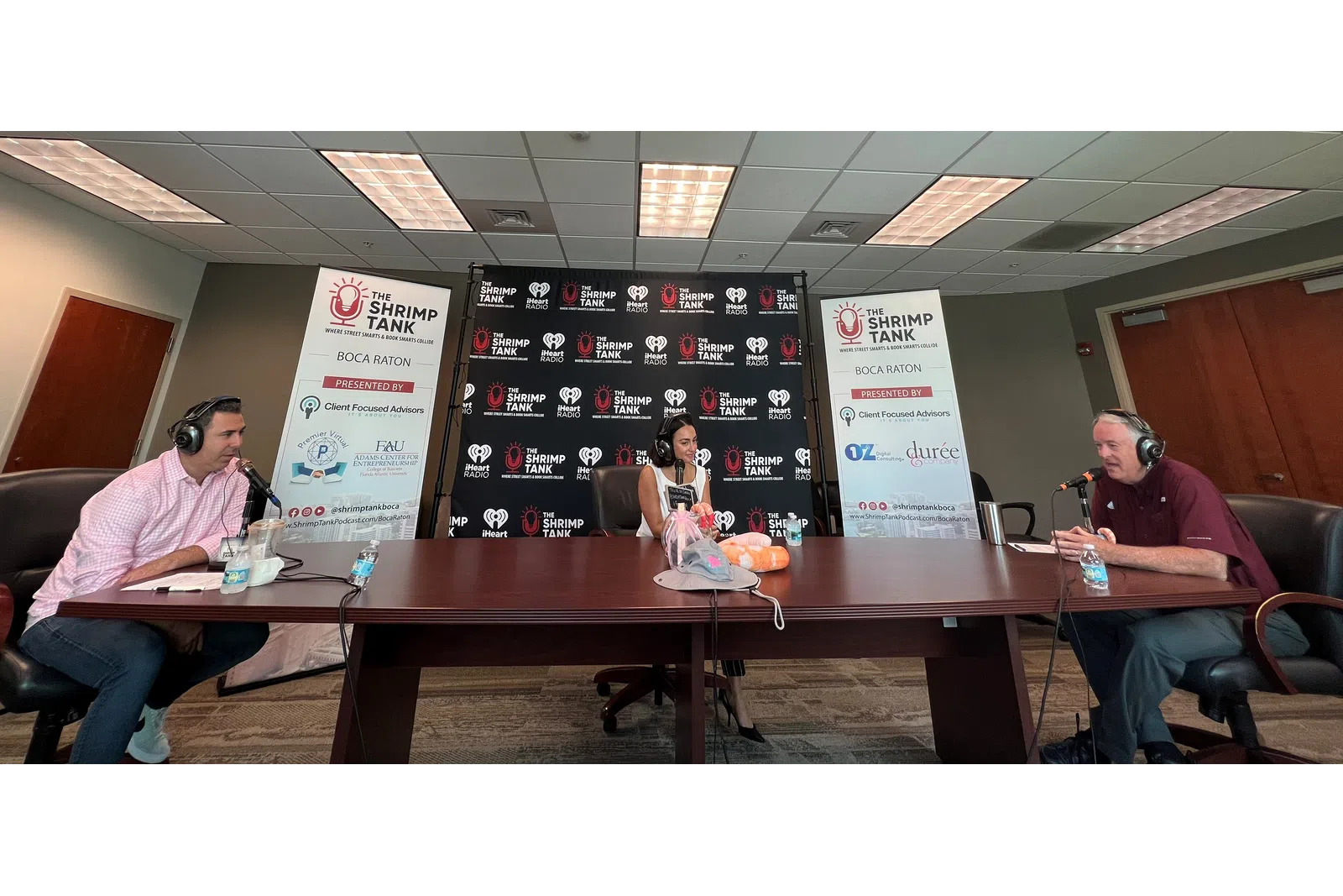 a group of people sitting at a table with a sign and a board