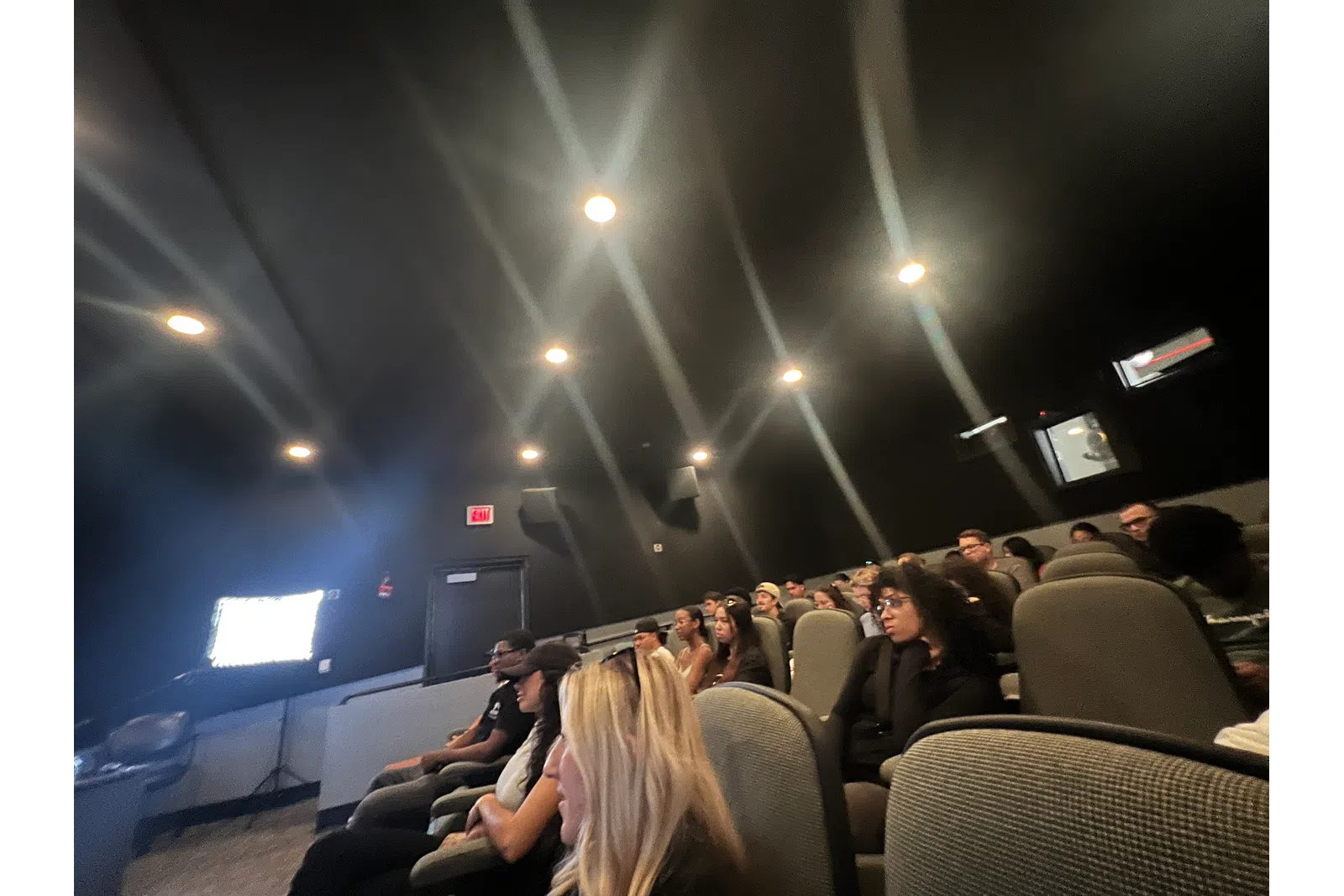 a group of people sitting in a room with a large screen