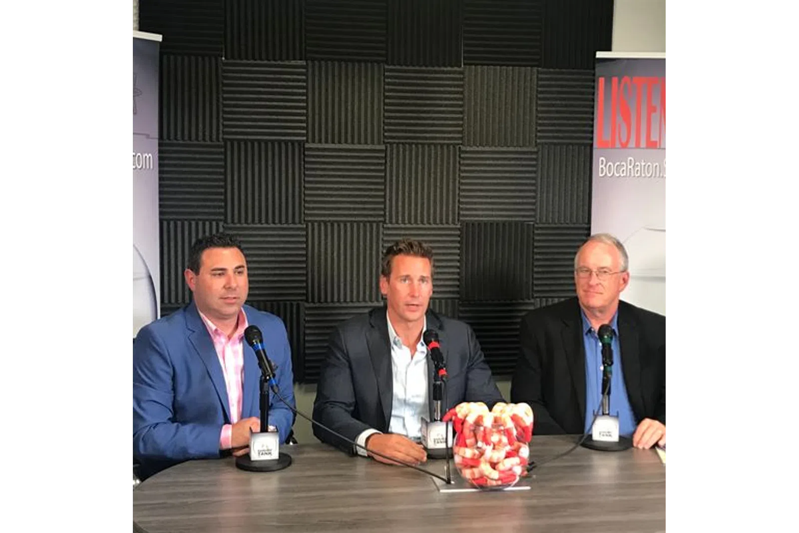 a group of men sitting at a table with microphones
