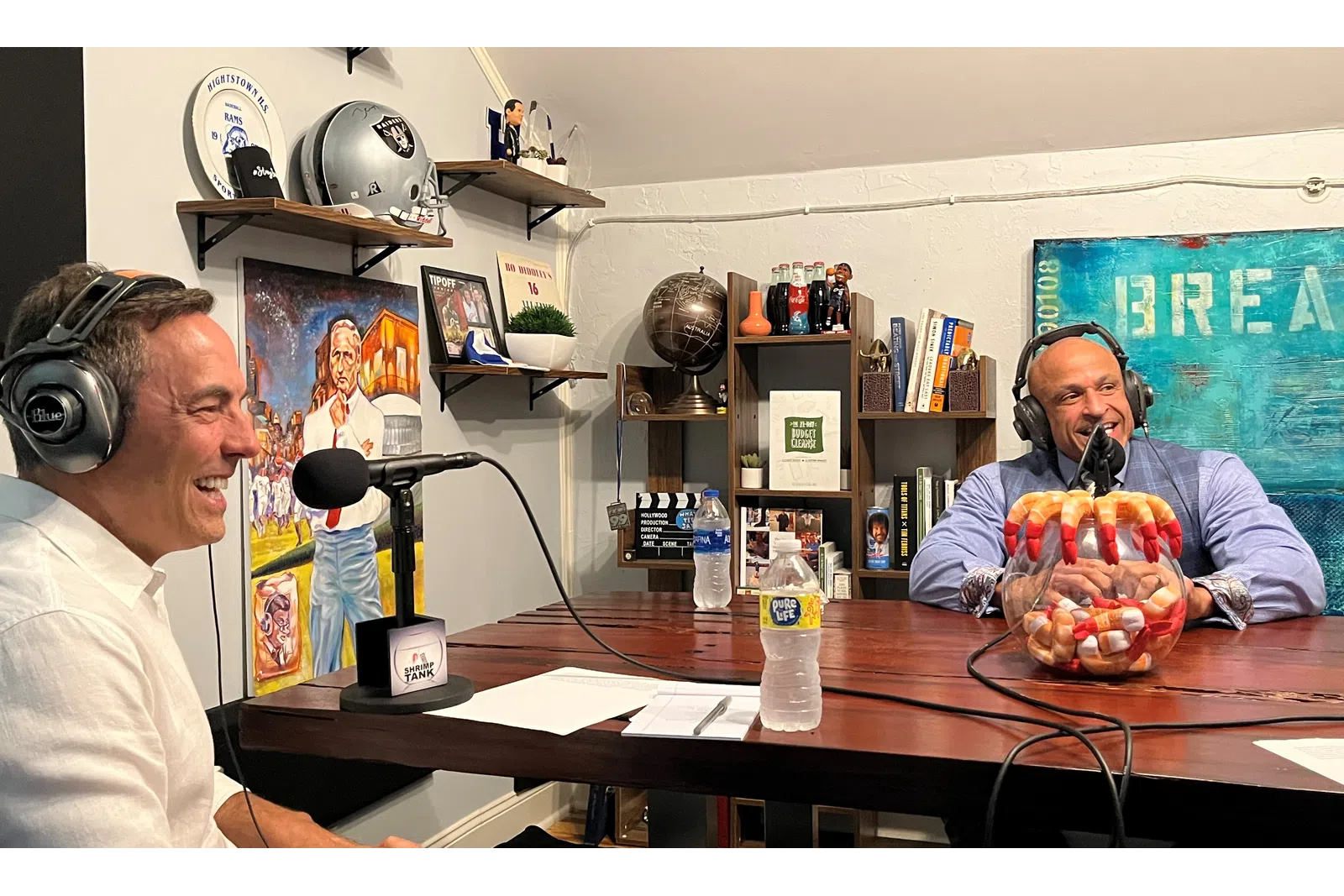 a man wearing headphones and sitting at a desk with a man wearing a mask