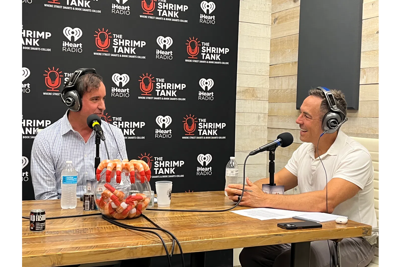 a couple of men wearing headphones and sitting at a table with microphones