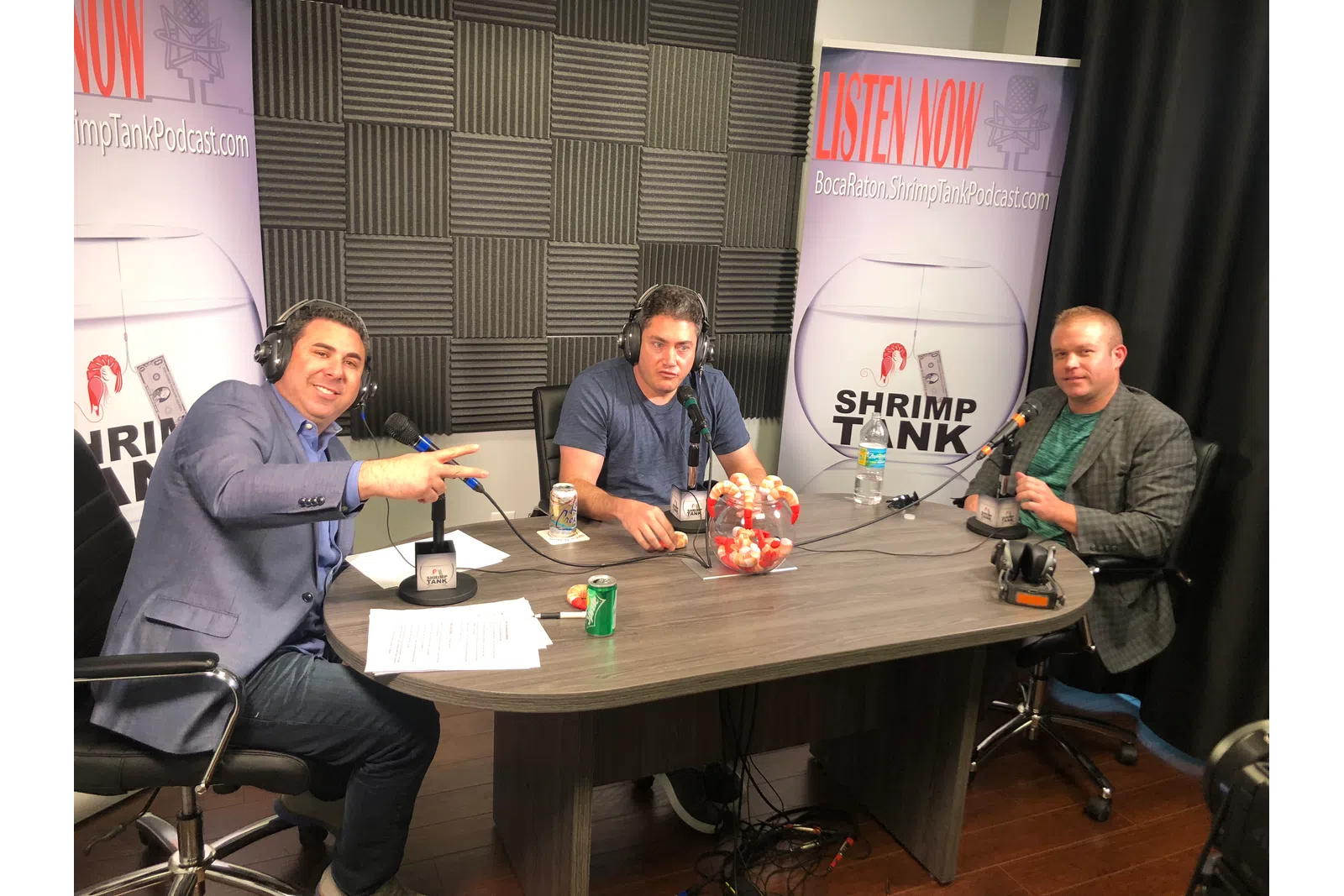 a group of men sitting at a table with a sign behind them