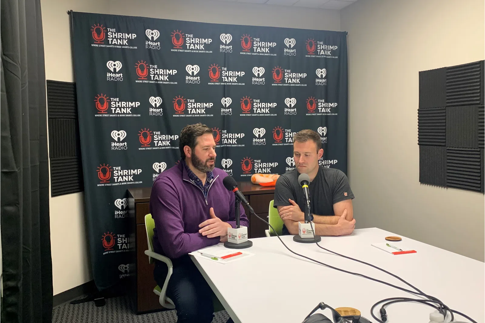 a couple of men sitting at a table with microphones