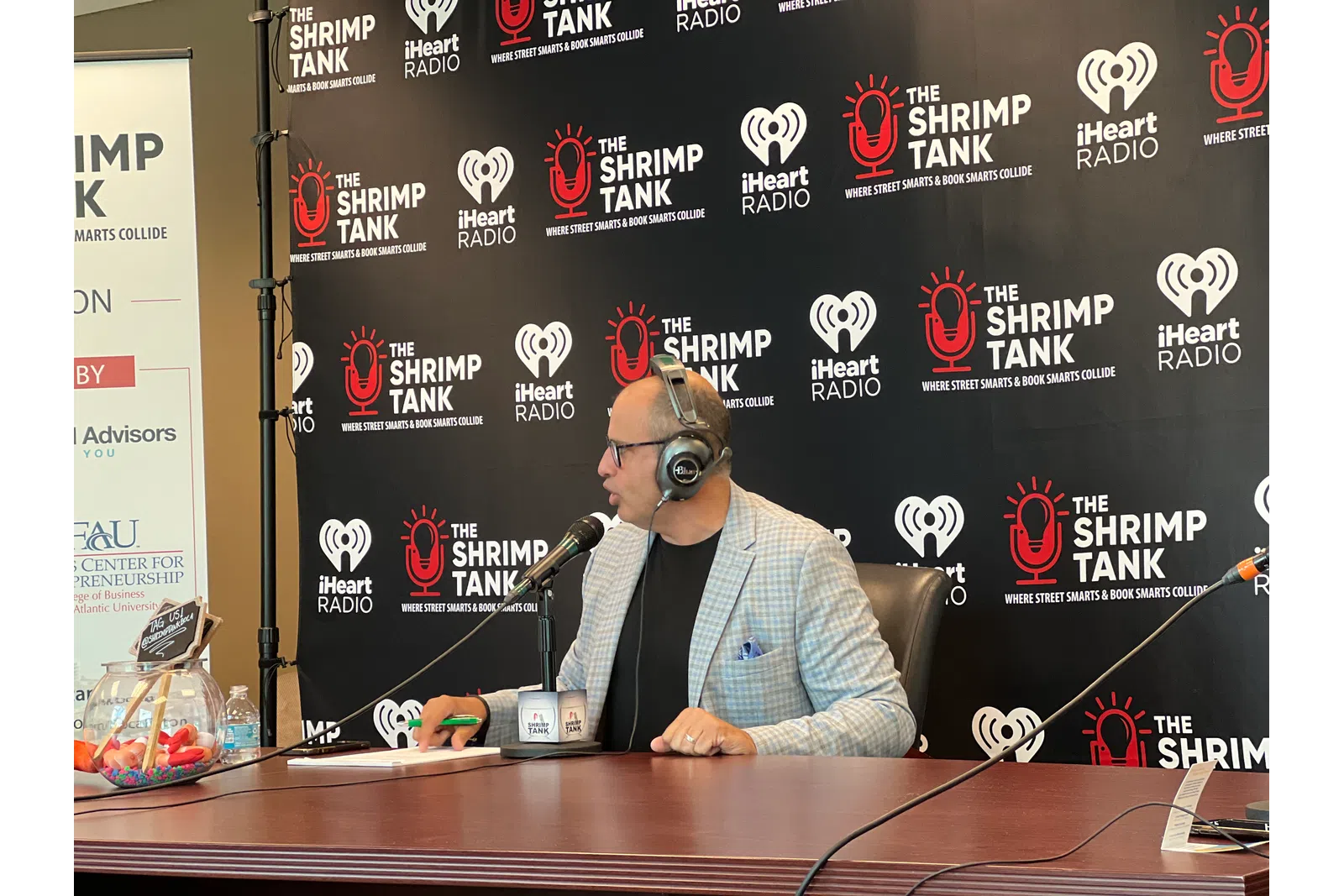 a person wearing headphones and sitting at a desk with a microphone