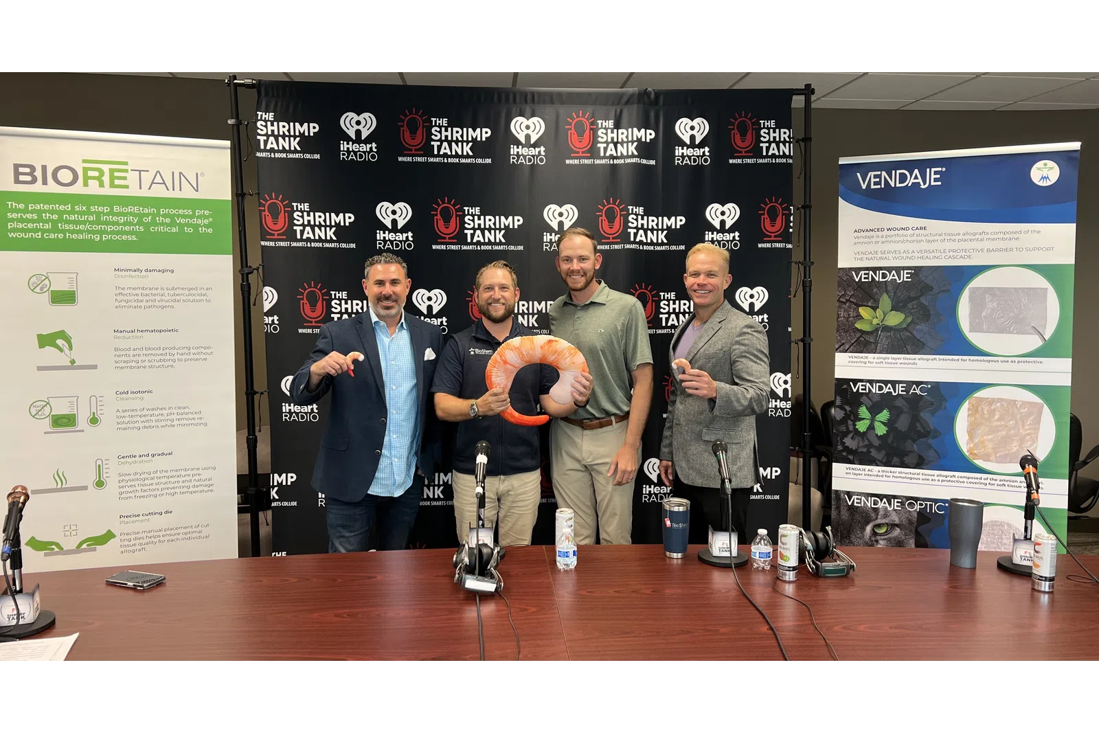 a group of men standing next to a table with microphones