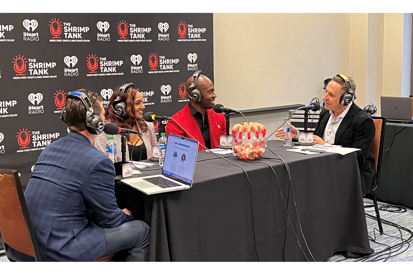 a group of people sitting at a table with microphones and a laptop