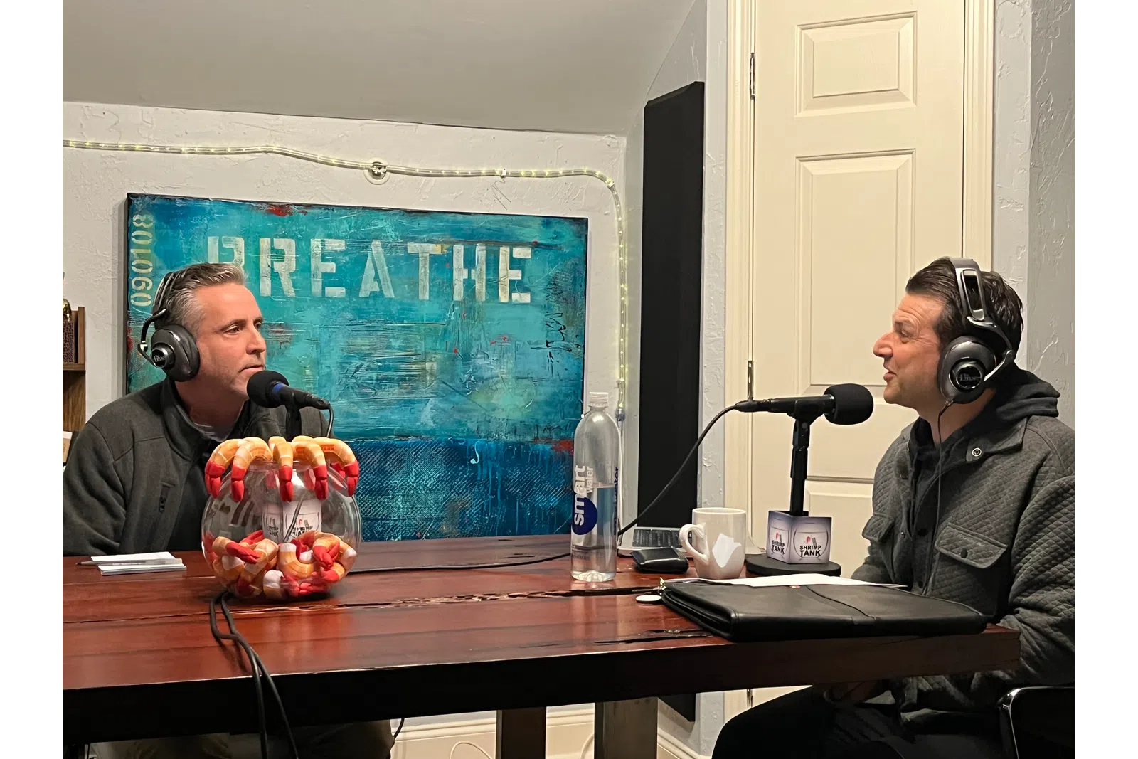 a couple of men wearing headphones and sitting at a table with a microphone