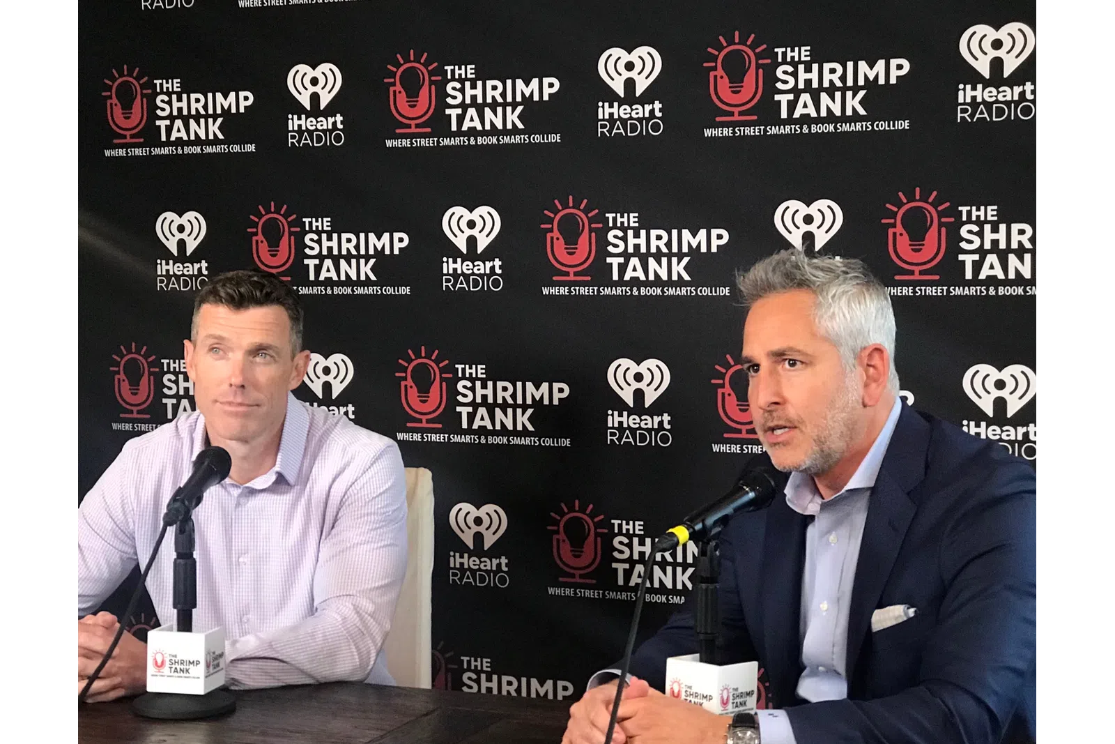a couple of men sitting at a table with microphones