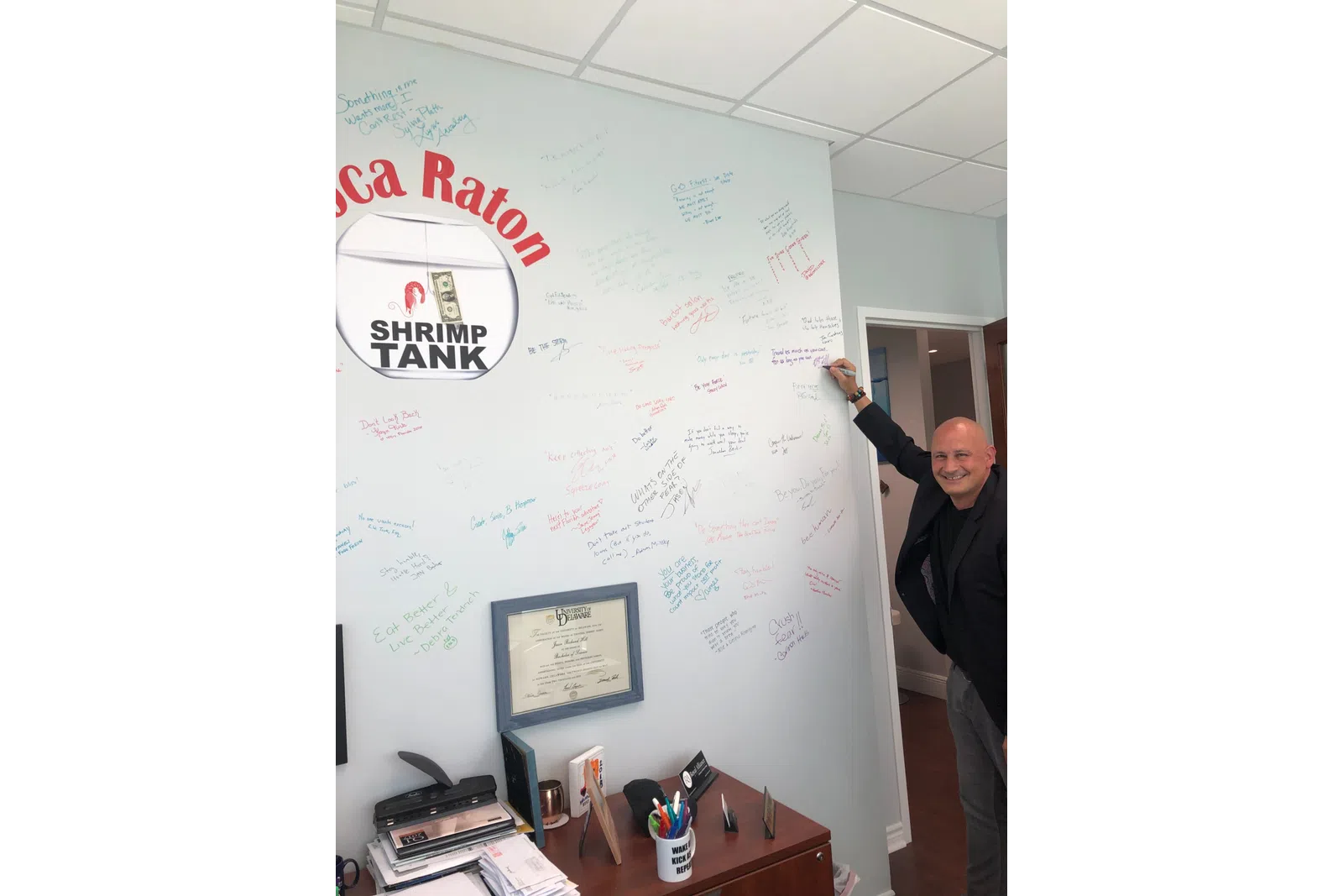a man standing next to a white board with drawings on it