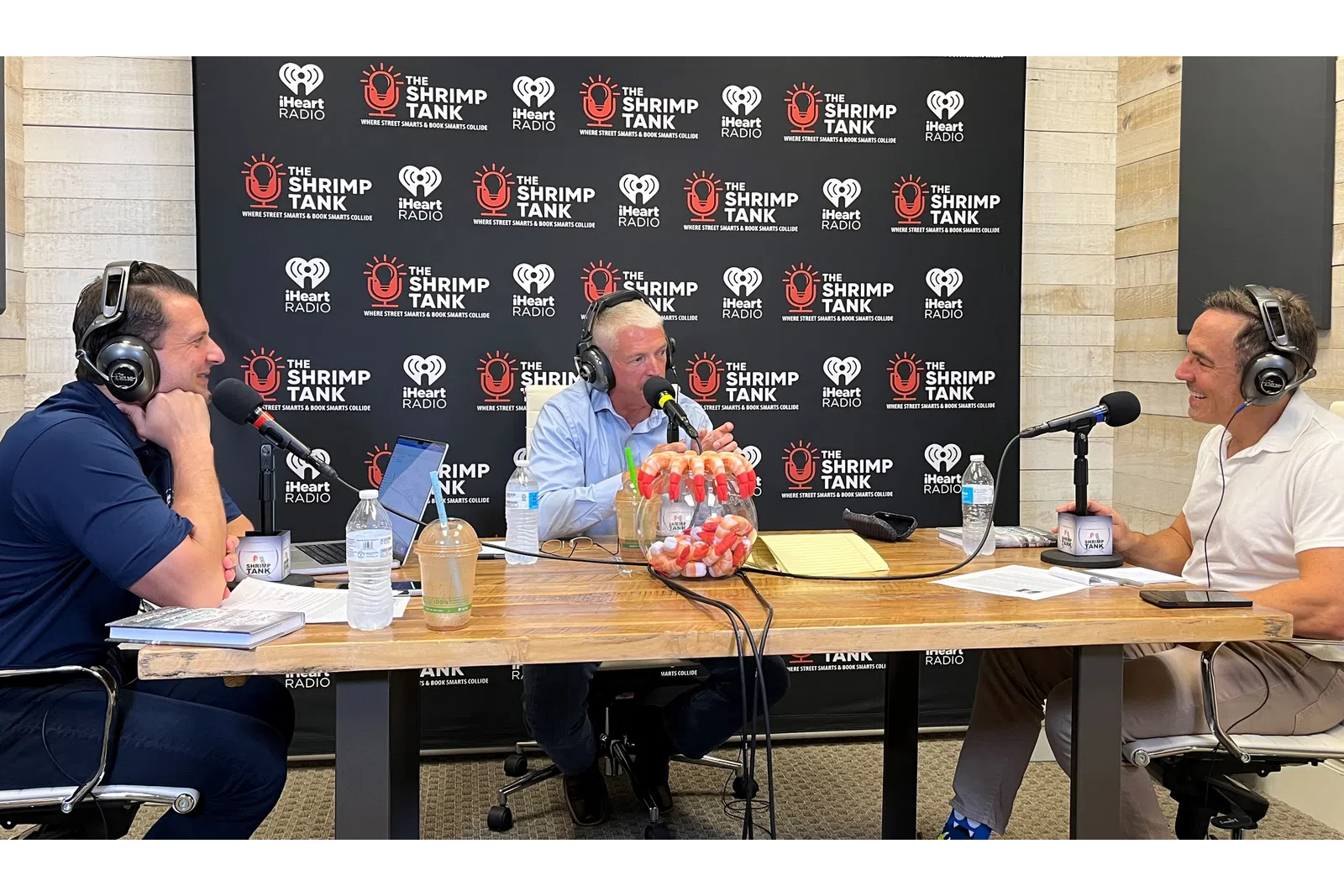 a group of people sitting at a table with microphones and a blackboard