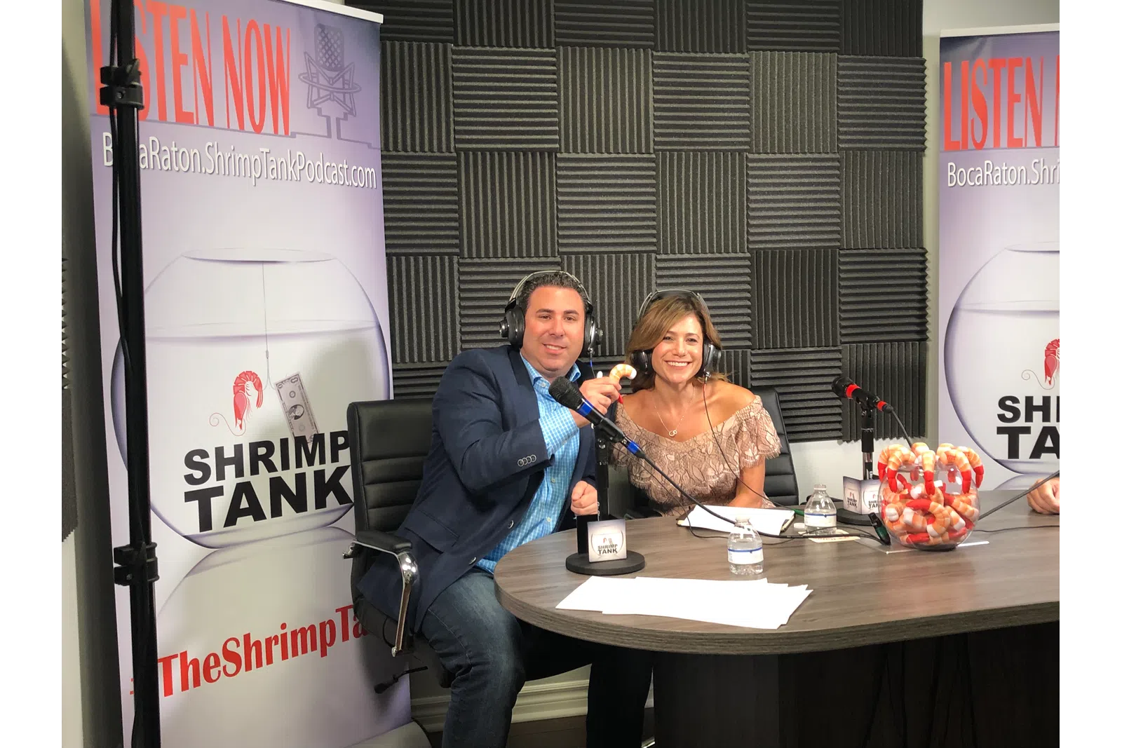 a man and woman sitting at a table with a microphone