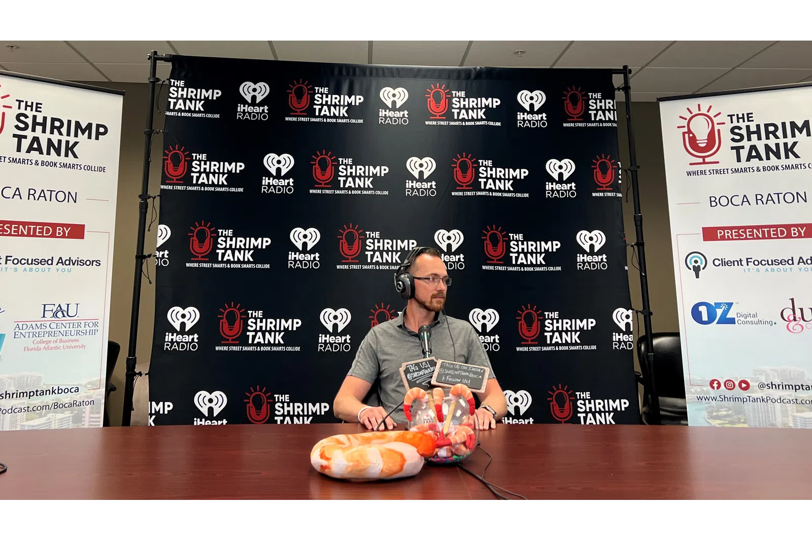 a person sitting at a table with a plate of food and a sign behind him