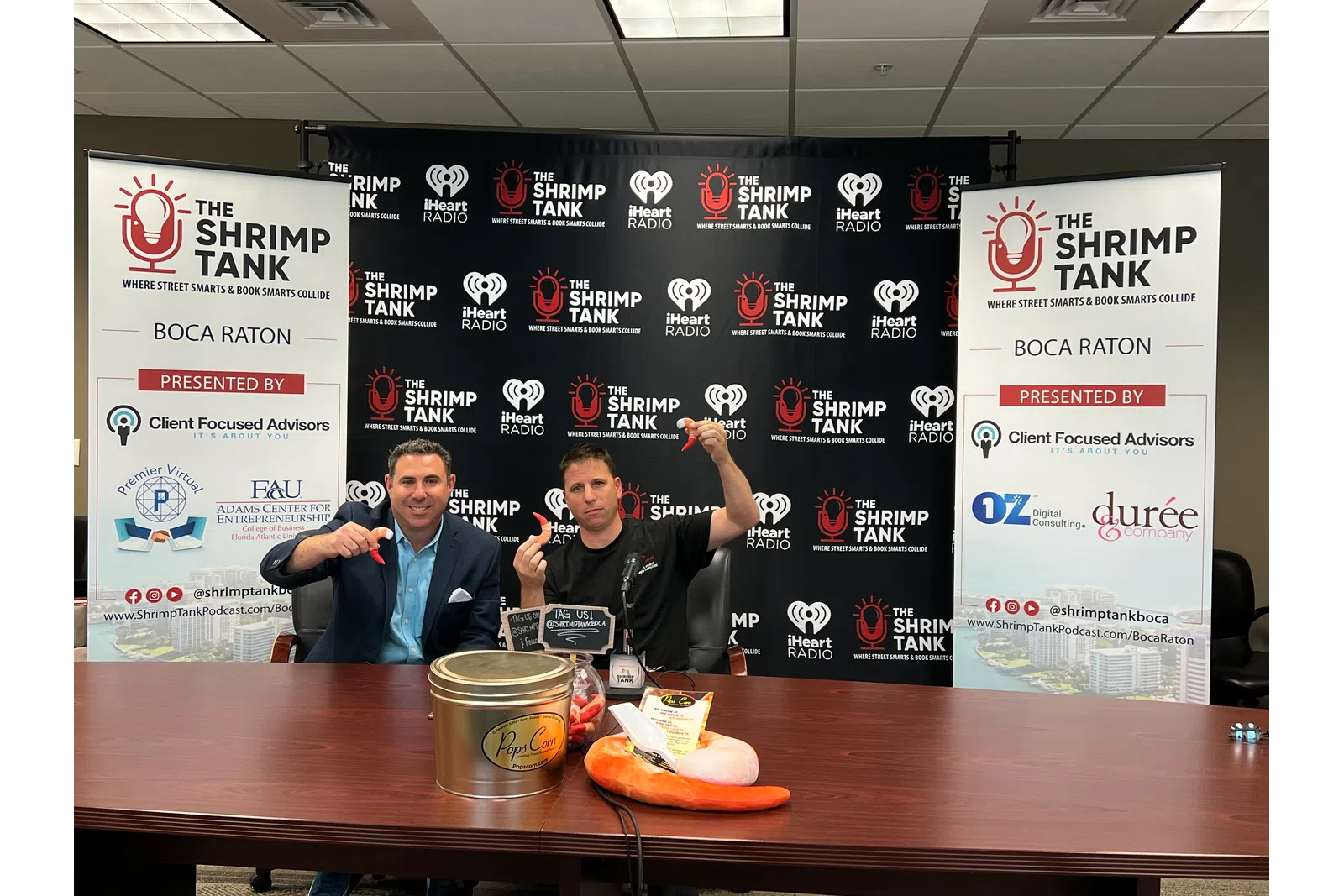 a couple of men sitting at a table with food and signs