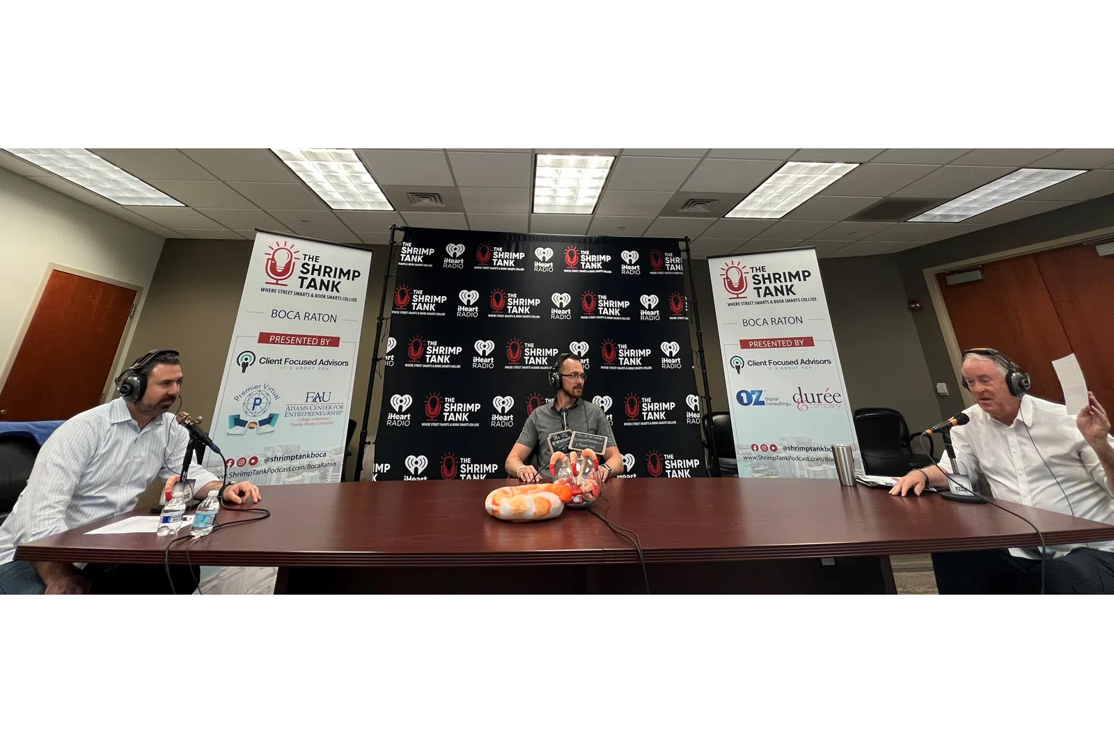 a group of people sitting at a table with microphones and a sign