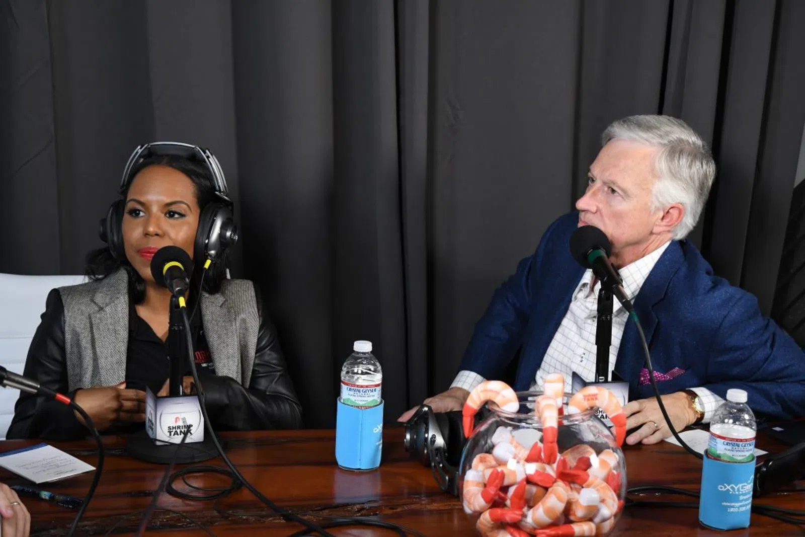 a man and woman sitting at a table with microphones