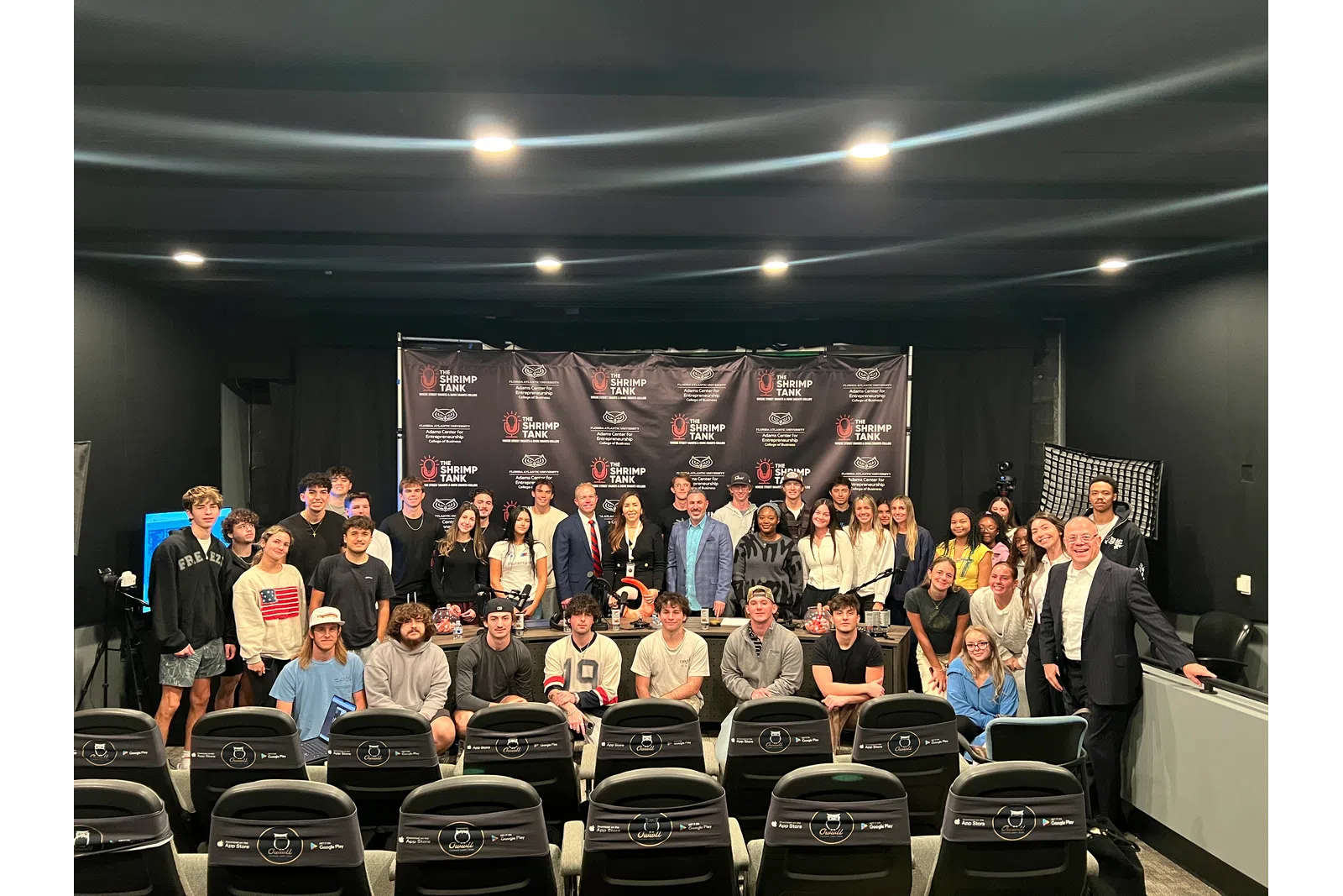Group of diverse people posing in front of Shrimp Tank Media branding backdrop in a studio setting