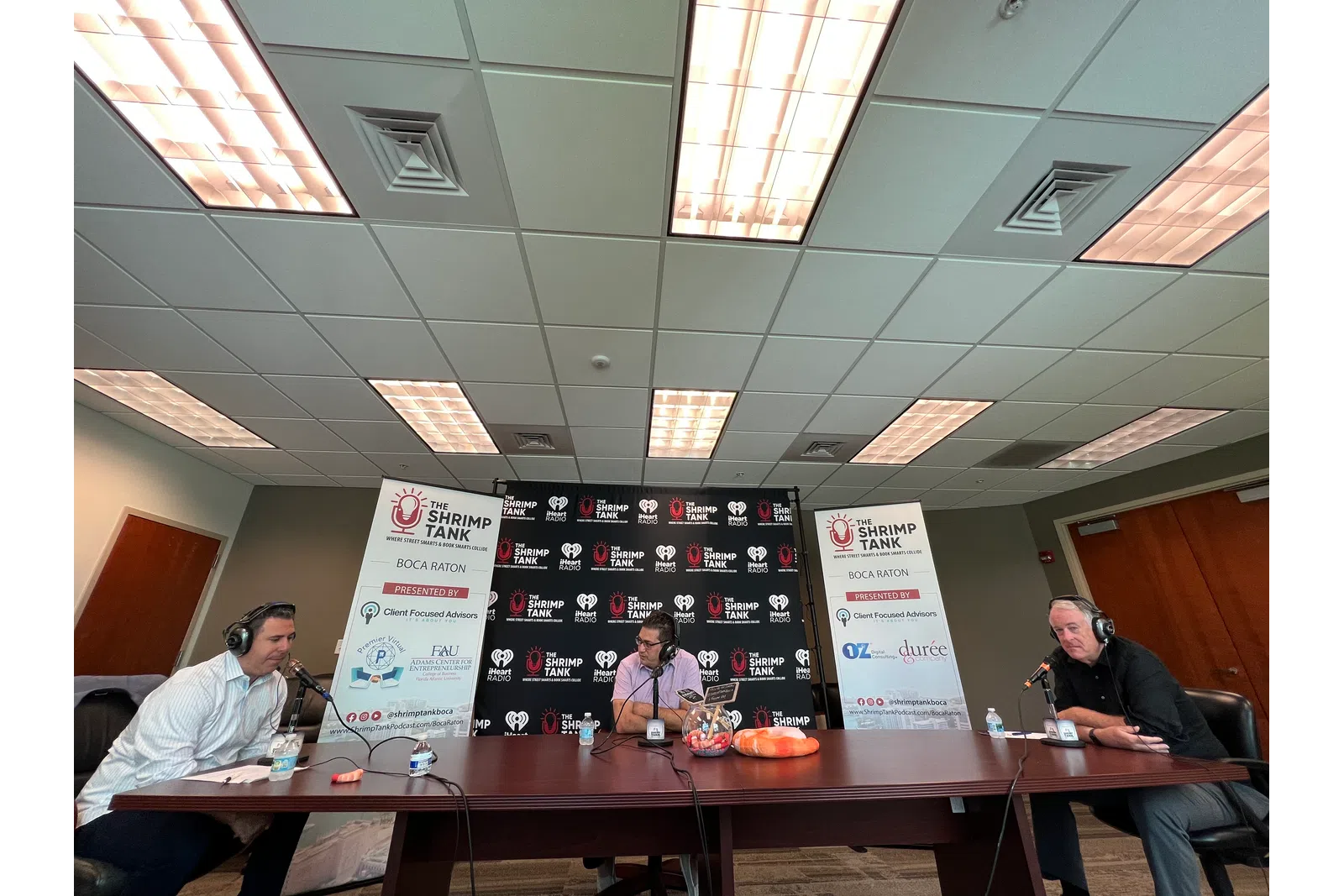 a group of people sitting at a table with a sign in front of them