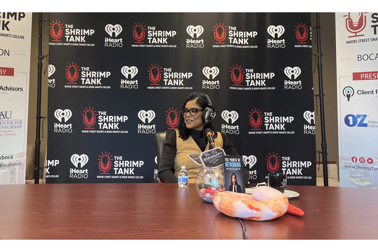 a person sitting at a table with a hot dog and a sign behind the