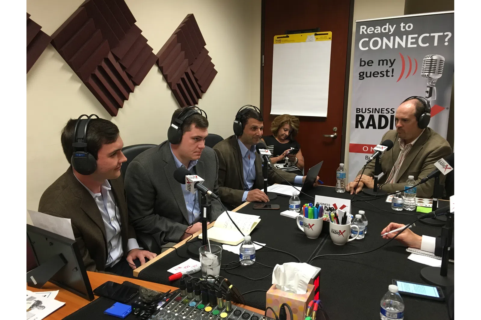 a group of people sitting at a table with microphones