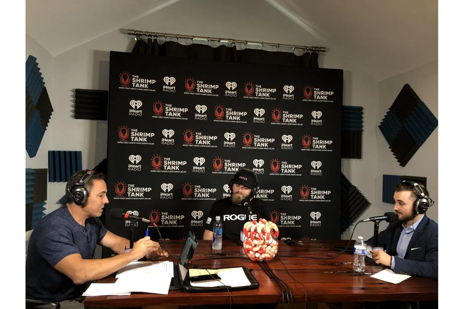 a group of people sitting at a table with microphones and a blackboard
