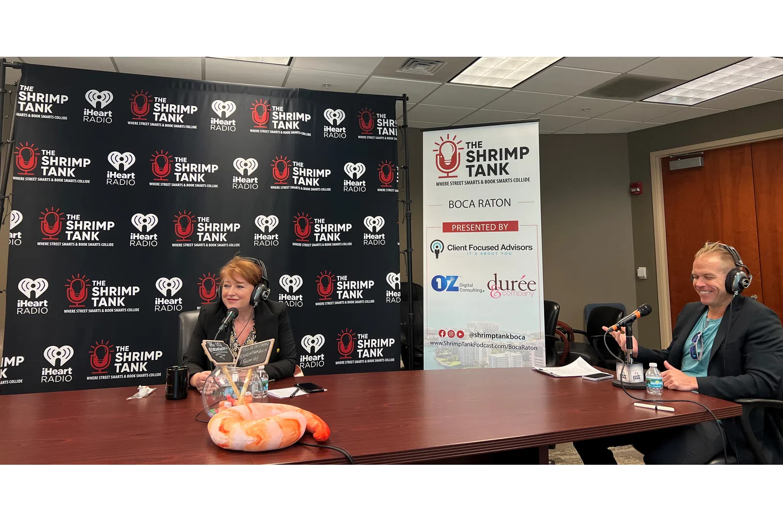 a man and woman sitting at a table with microphones