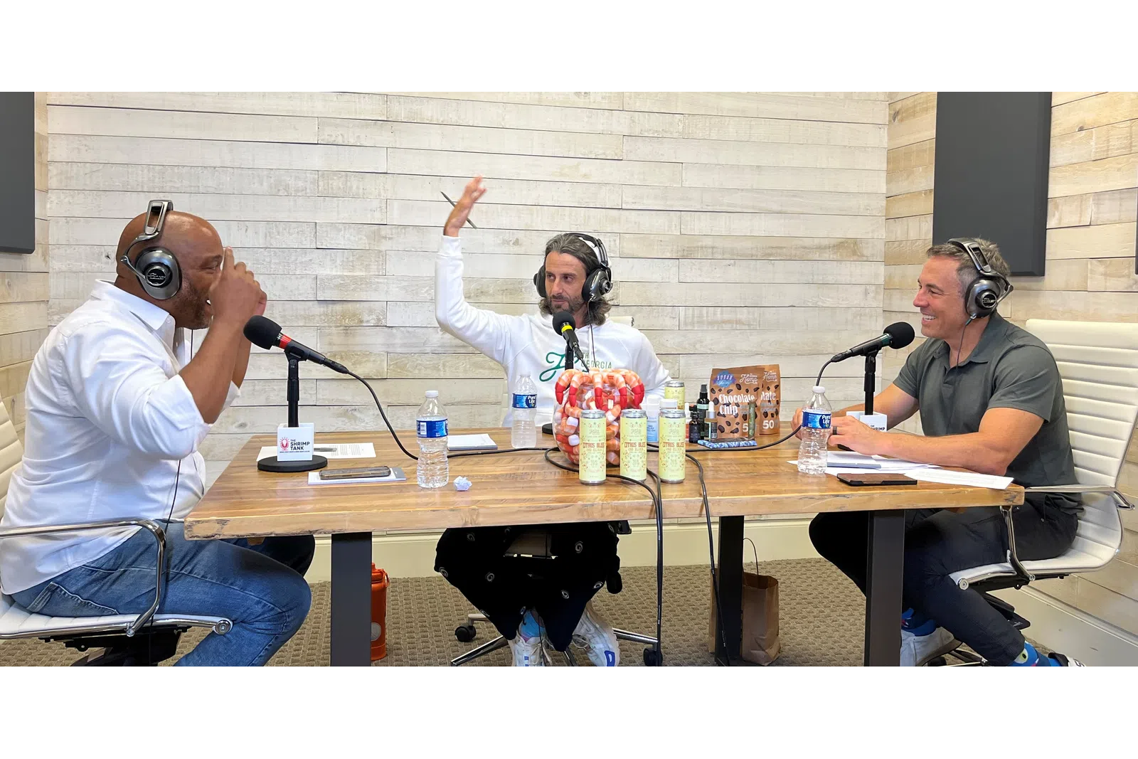 a group of people sitting at a table with microphones and drinks