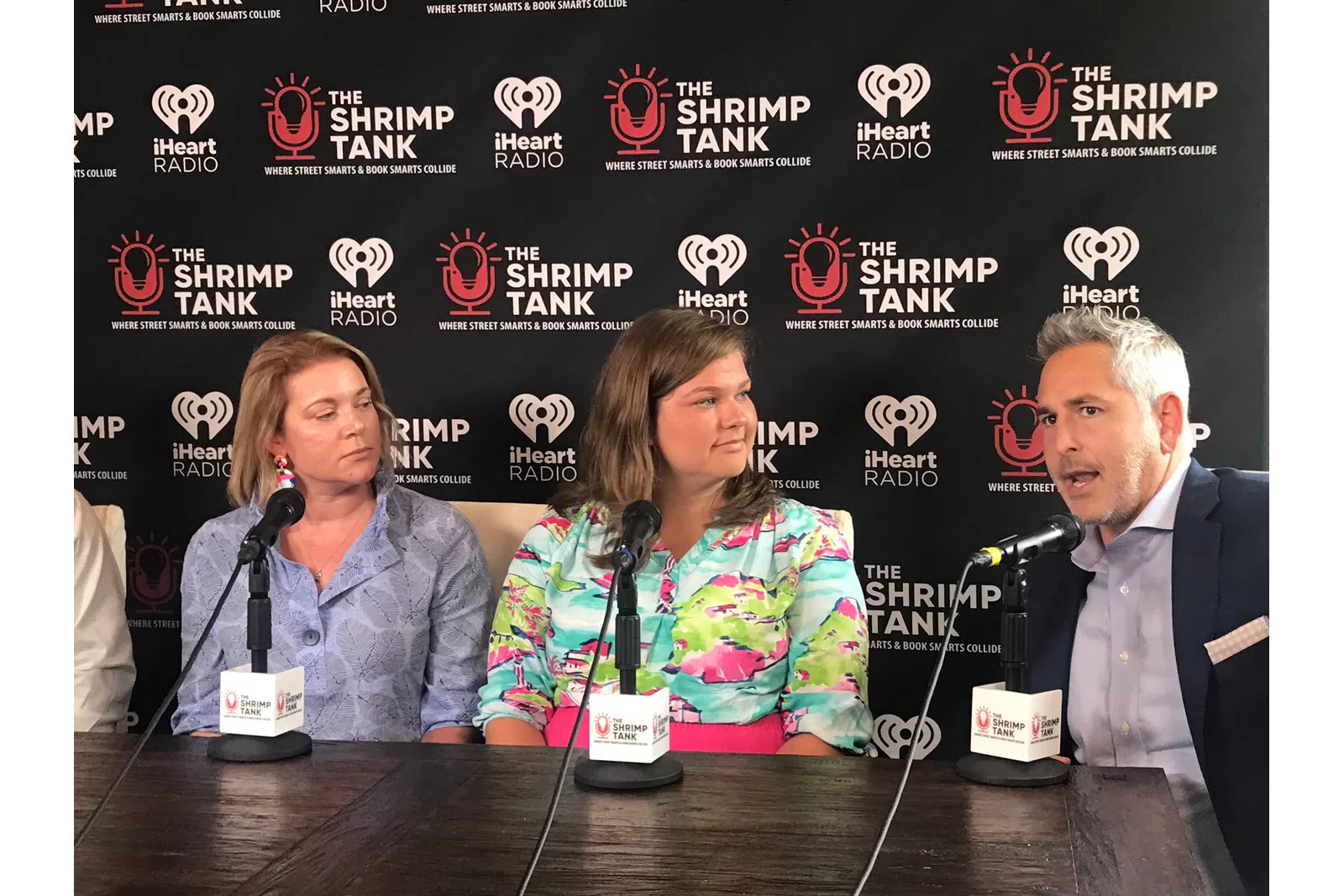 a group of people sitting at a table with microphones