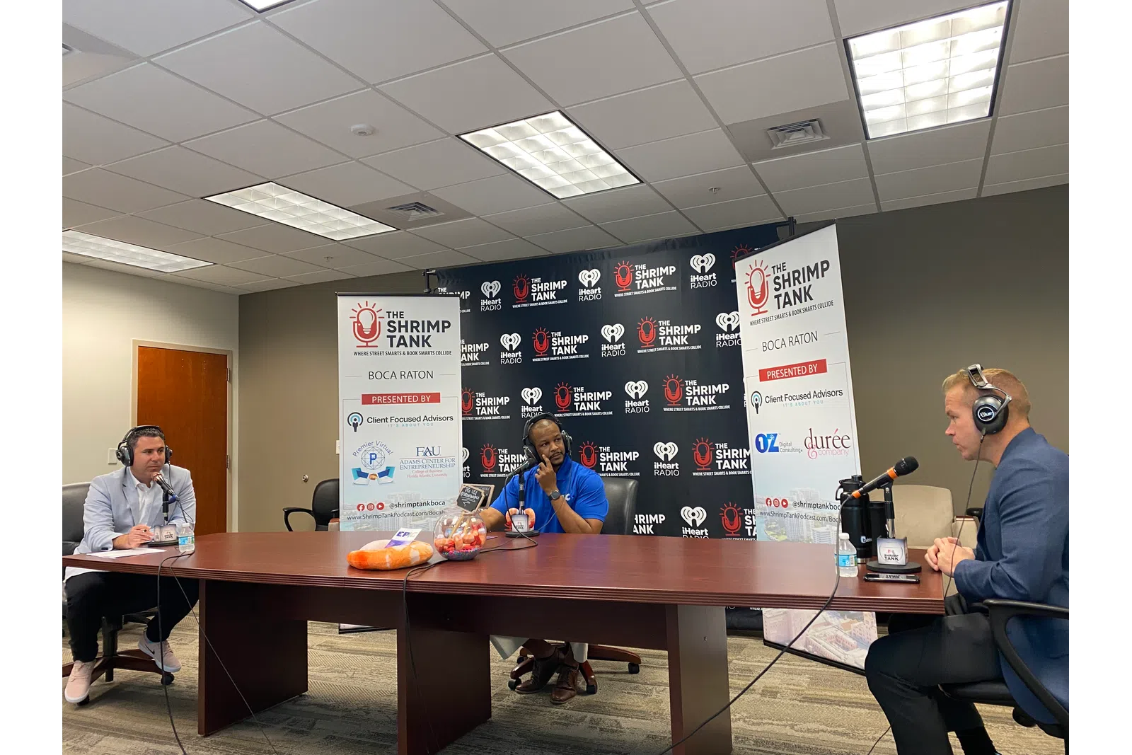 a group of people sitting at a table with microphones and a sign