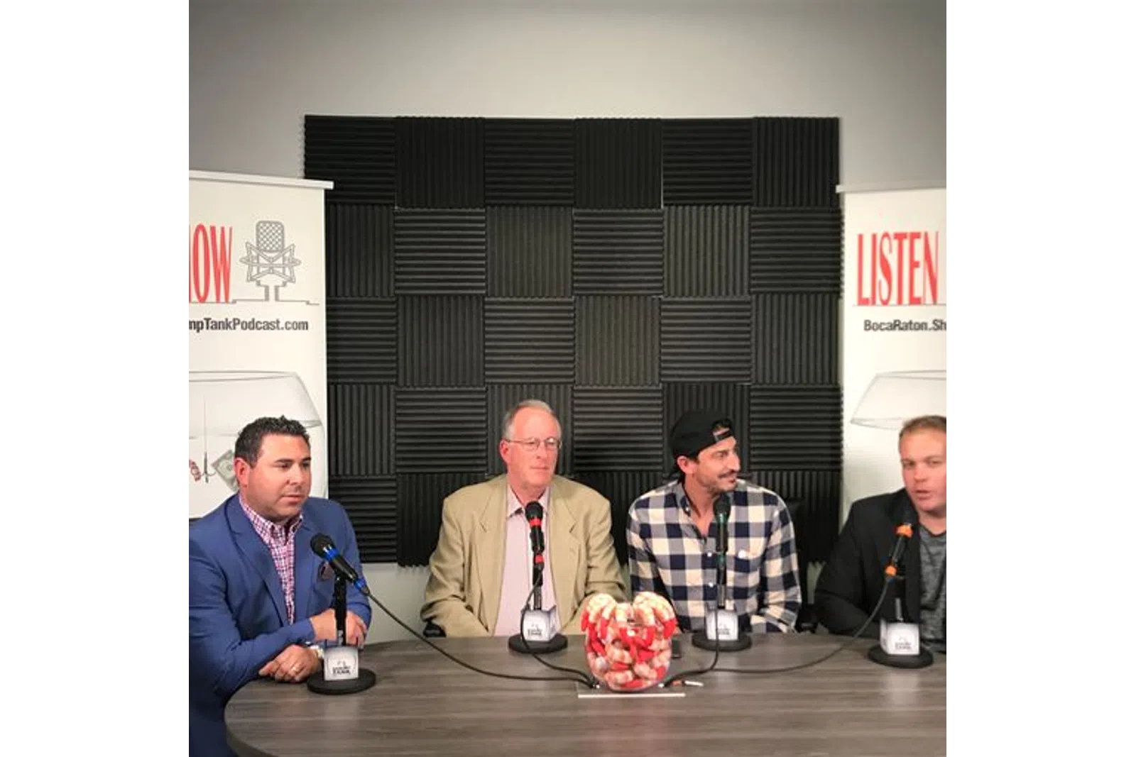a group of men sitting at a table with microphones