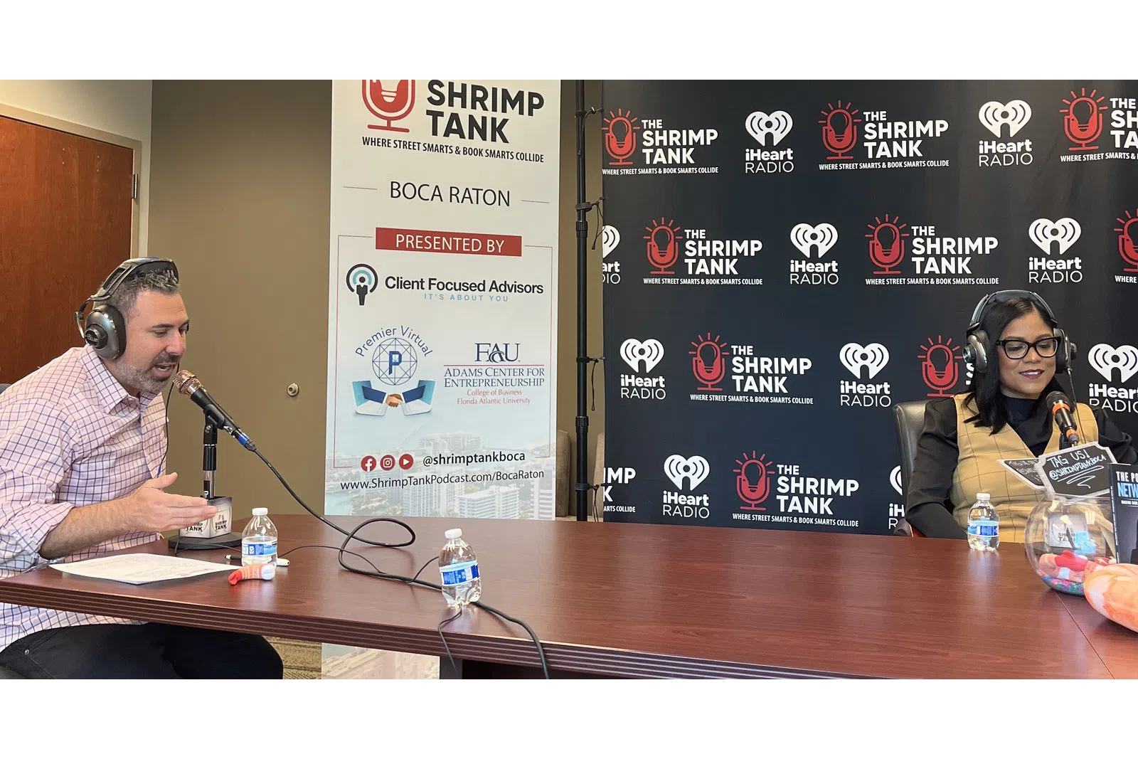 a man and woman sitting at a table with microphones
