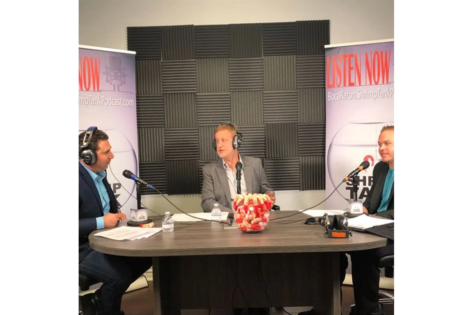 a person wearing headphones sitting at a table with microphones