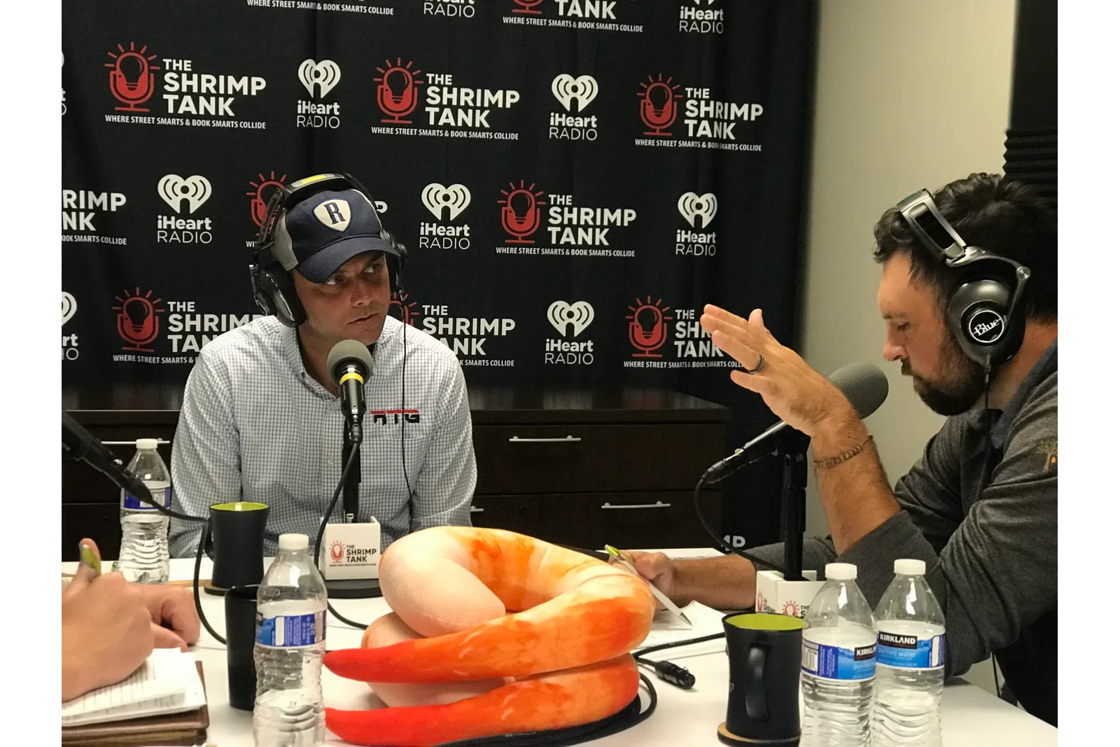 a man wearing headphones and sitting at a table with a man wearing a hat