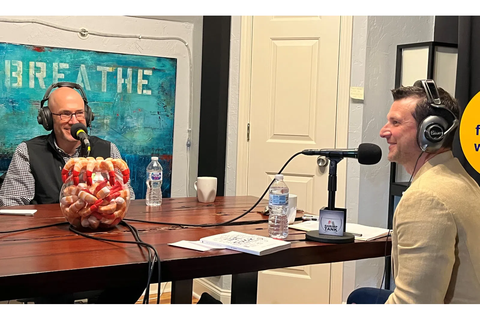 a couple of men wearing headphones and sitting at a table with a microphone
