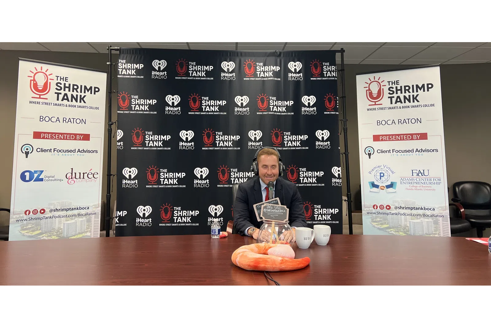 a person sitting at a table with a trophy and a sign behind him