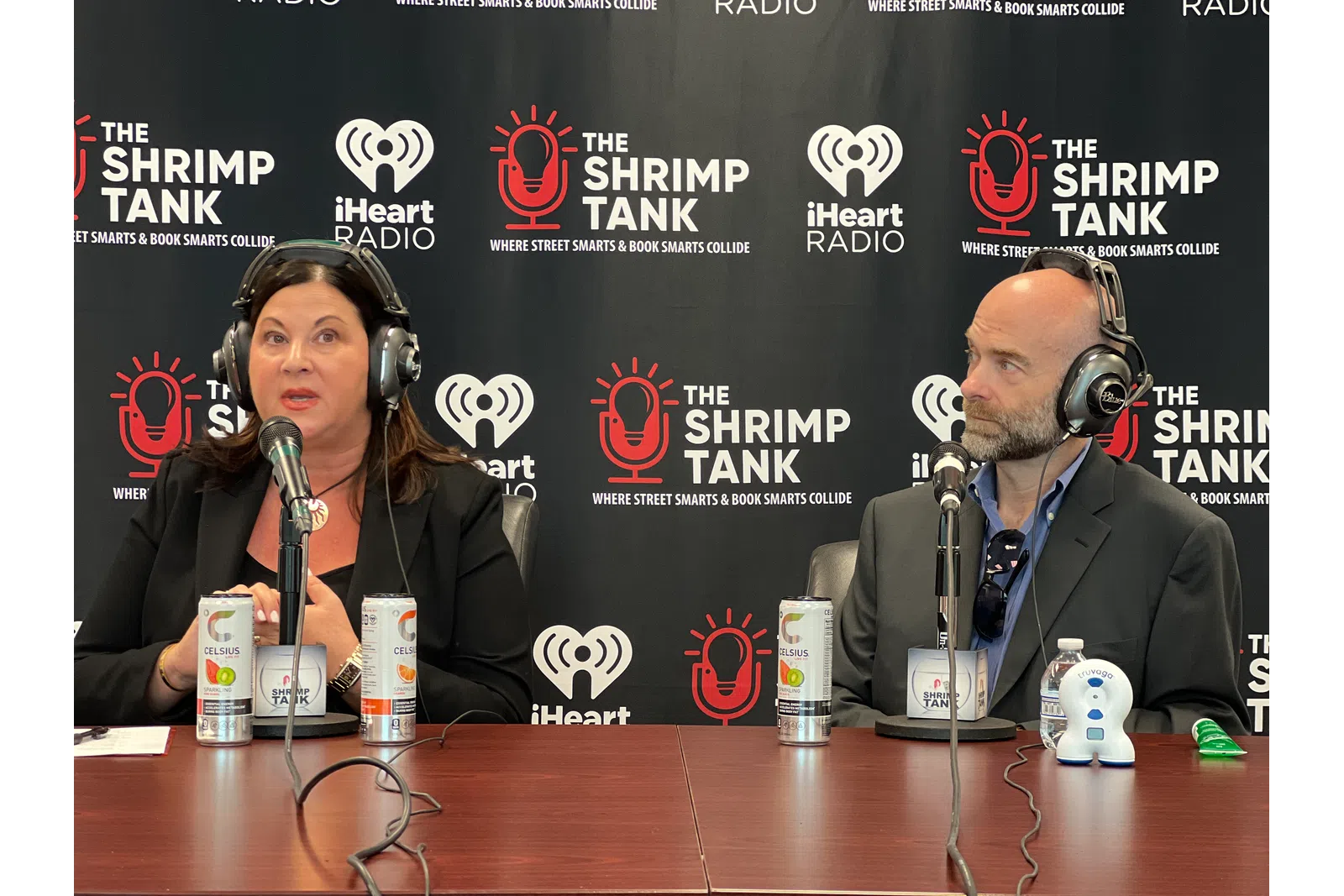a man and woman sitting at a table with microphones