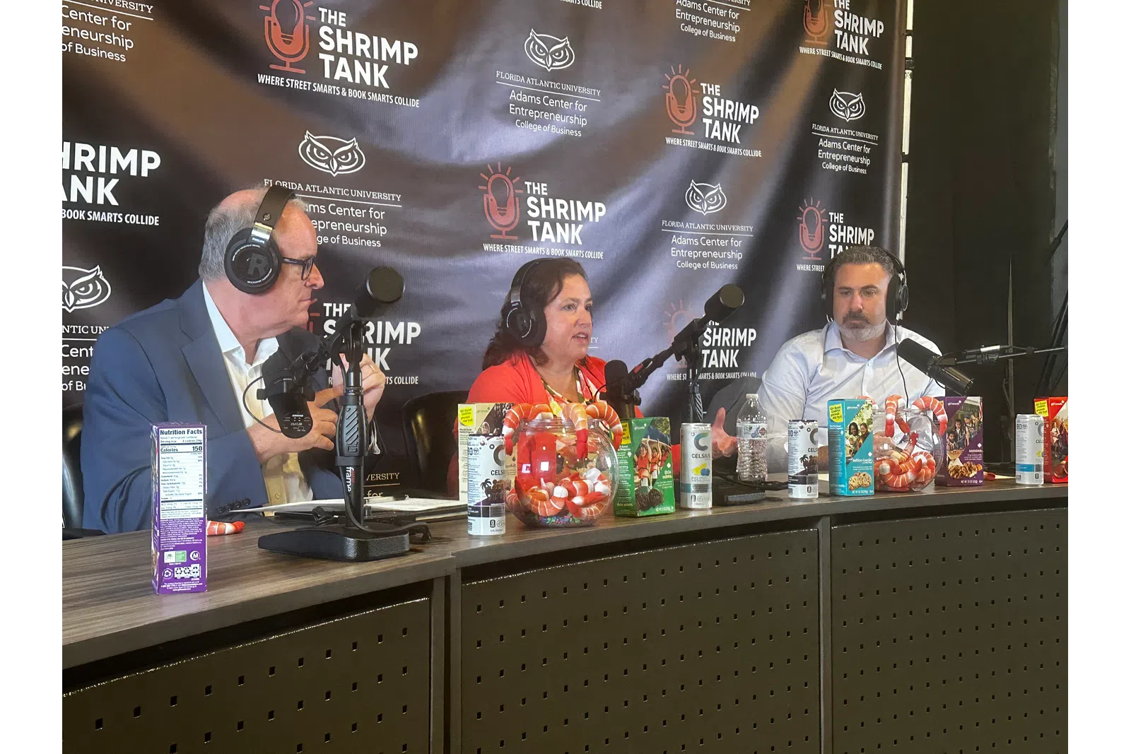 a group of people sitting at a table with microphones and drinks