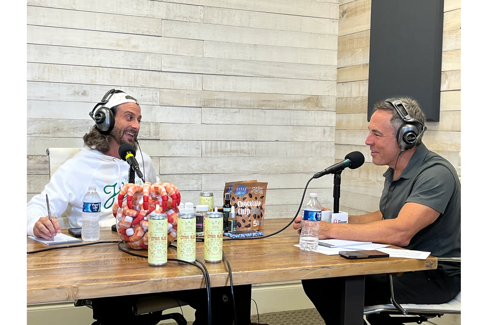 a man and woman sitting at a table with microphones and food