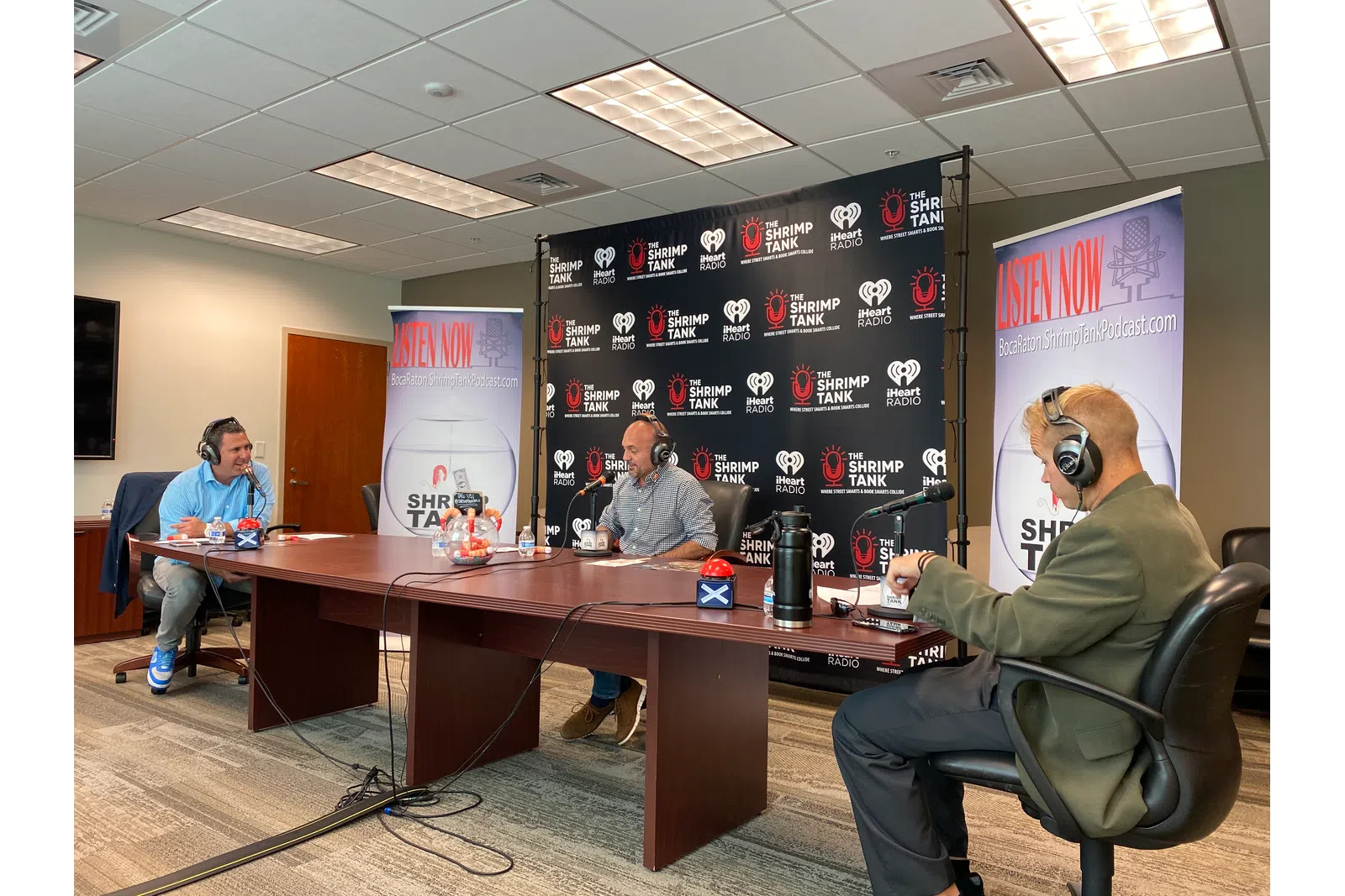 a man wearing headphones sitting at a table with a man in a suit and a woman in