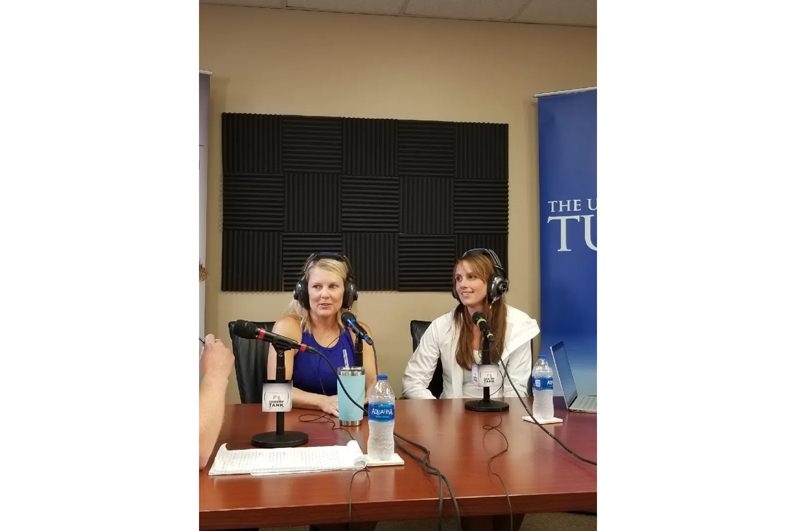 a couple of women sitting at a table with microphones