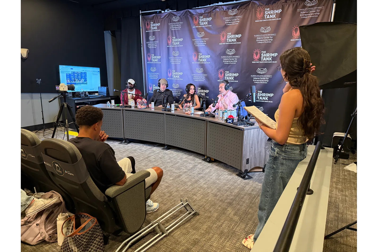 Panelists and host engaged in discussion at The Shrimp Tank event with audience and recording setup in studio