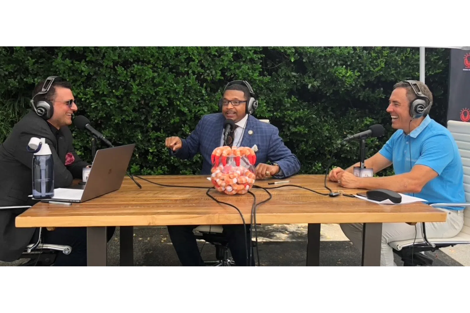 a group of men sitting at a table with laptops and microphones