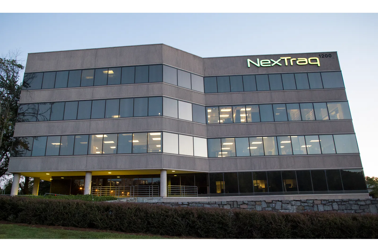 NexTraq office building at dusk with lights on inside and clear exterior windows.