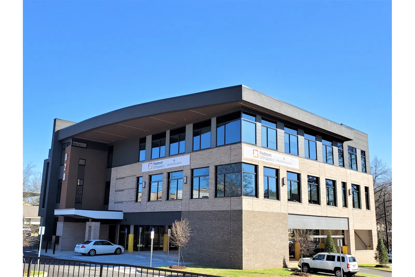 Modern three-story office building with large windows and clear blue sky background