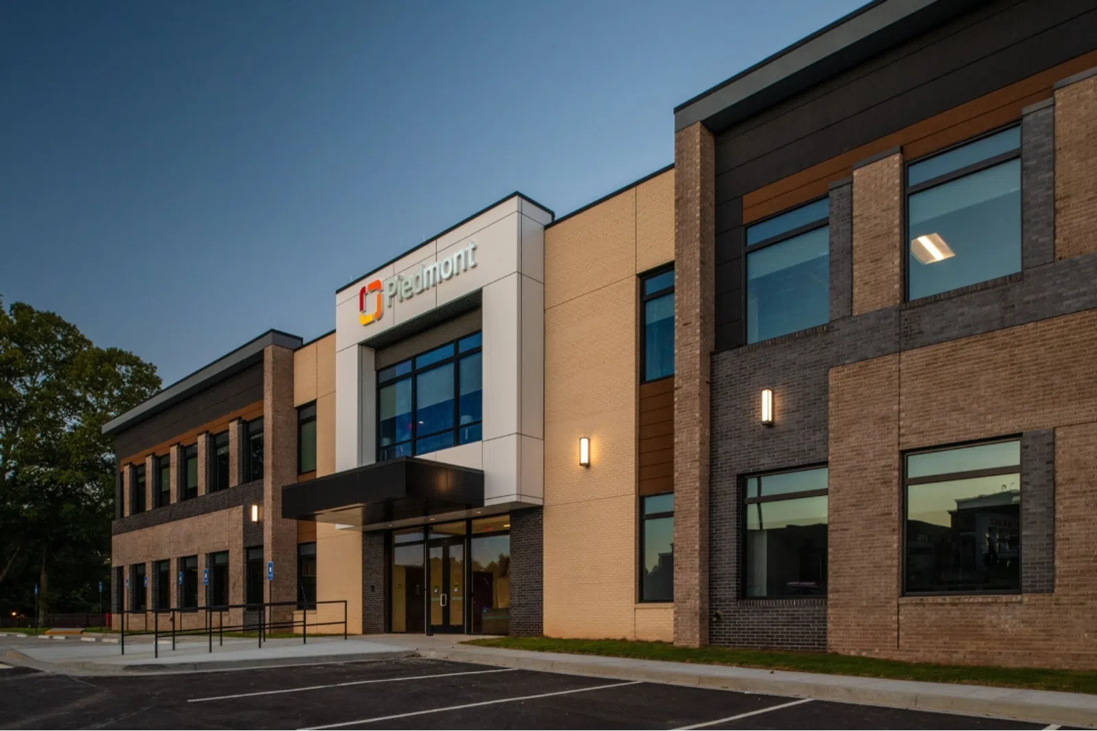 Modern Piedmont medical office building exterior at dusk with parking lot and illuminated signage.