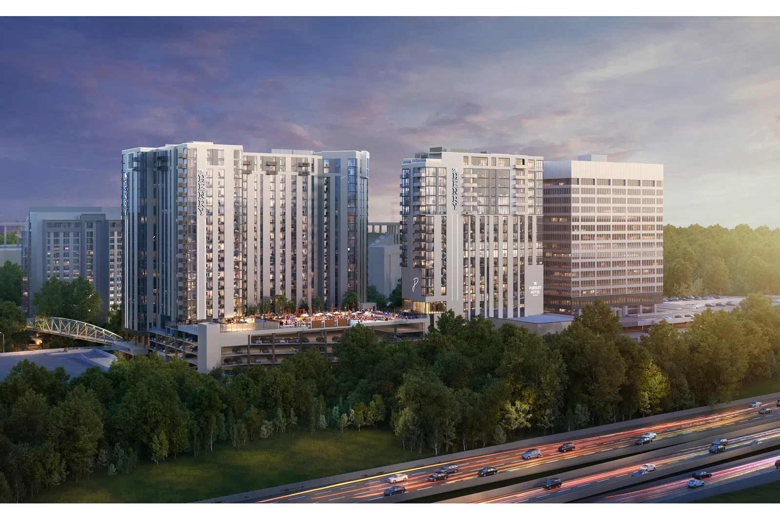 Modern residential and office buildings beside a highway with trees and a colorful sunset sky.
