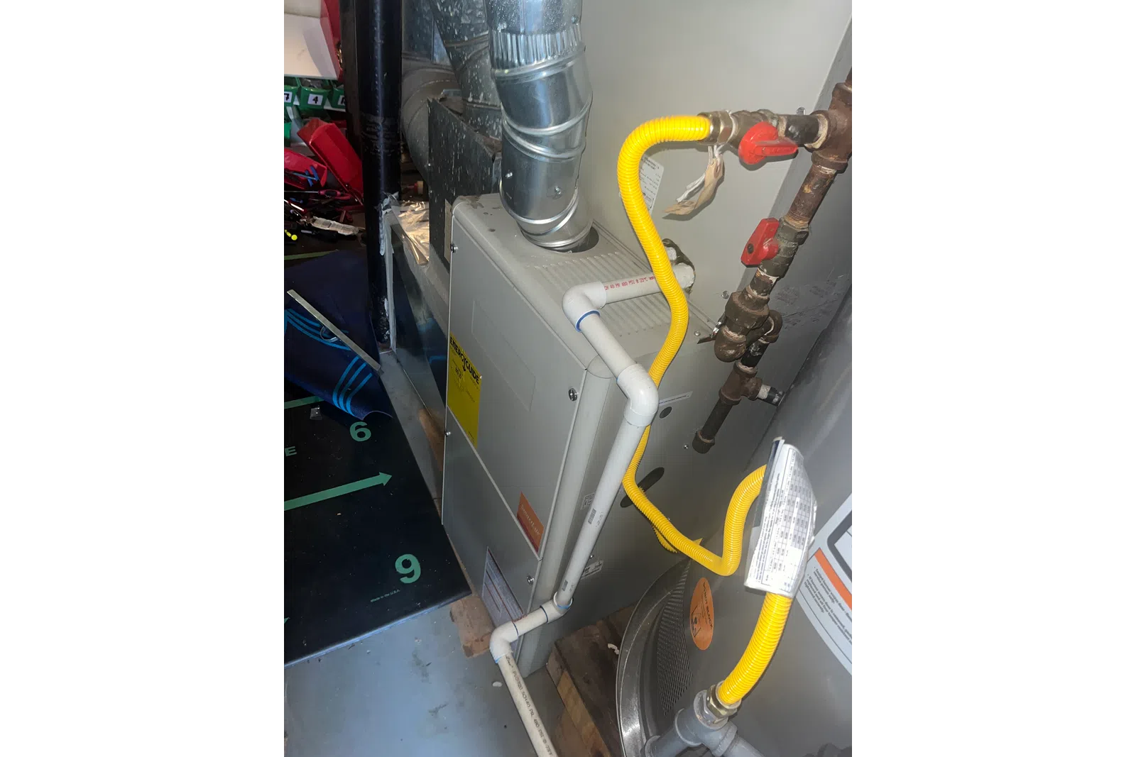 AC Preventative Maintenance in Tucker, Atlanta by The Air Company of GA. Close-up of a home furnace system with metal vent pipes and yellow gas tubing connected to plumbing.