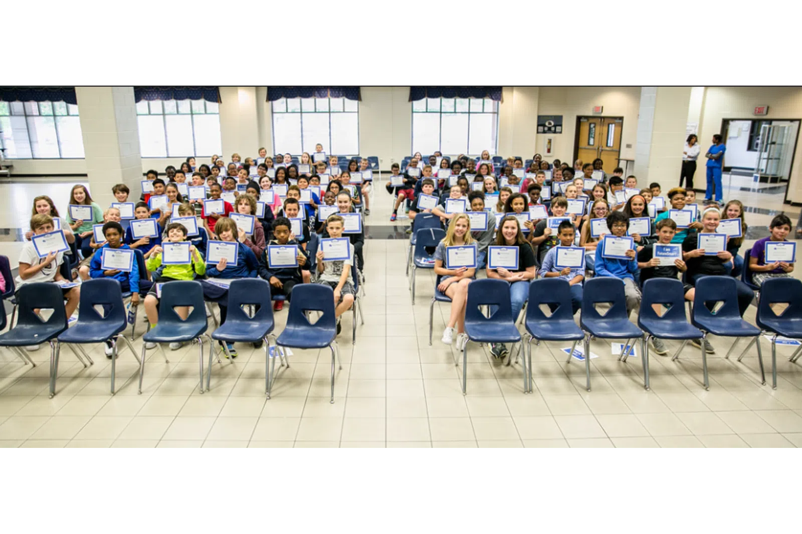 a group of people sitting in chairs with laptops in their hands
